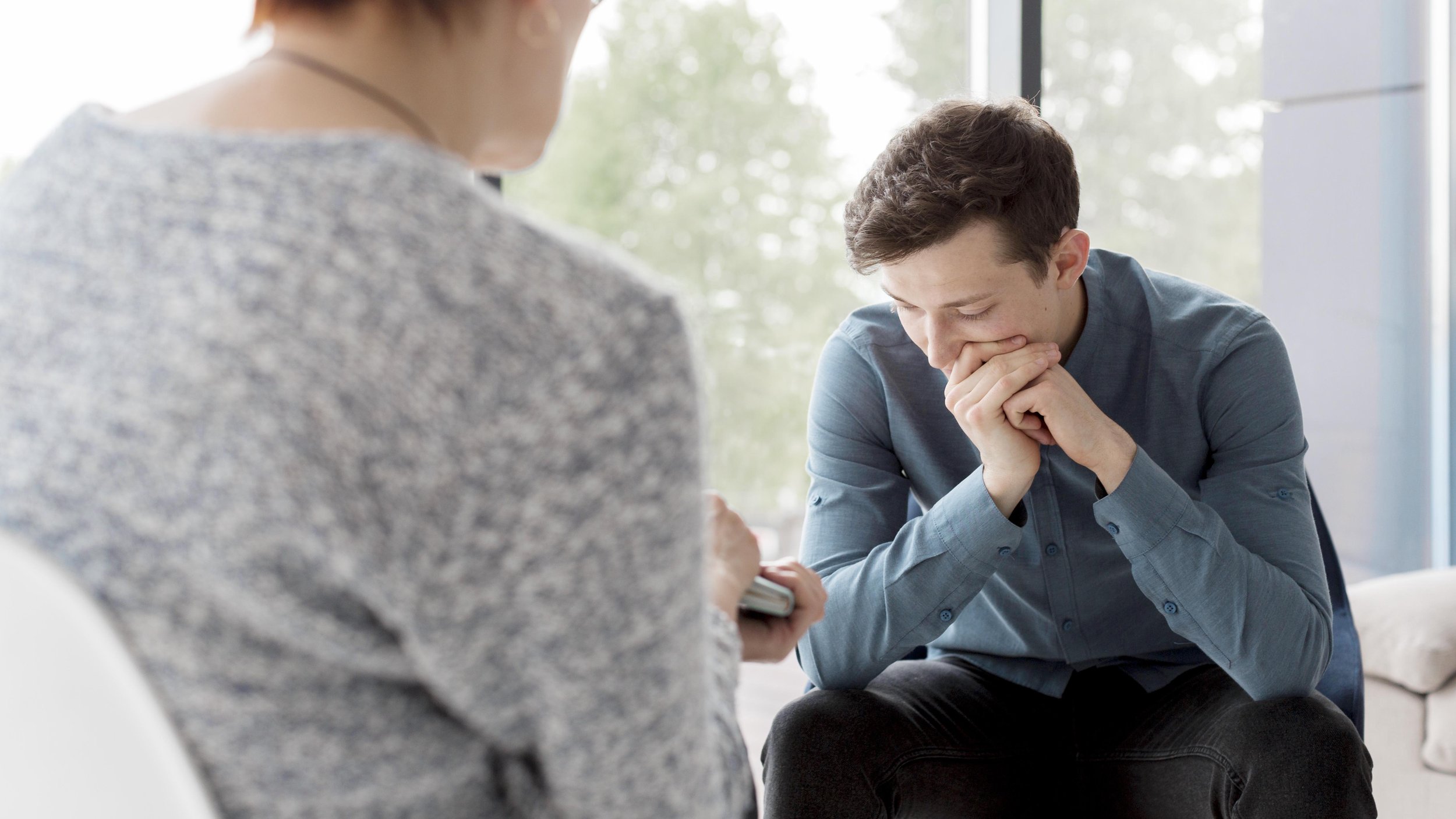 Male client speaking with therapist during a counseling session focused on stress and emotional wellbeing.
