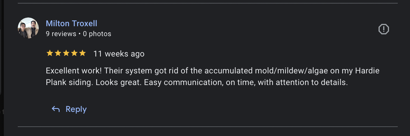 Two men sitting together smiling, in an indoor setting with large windows in the background.