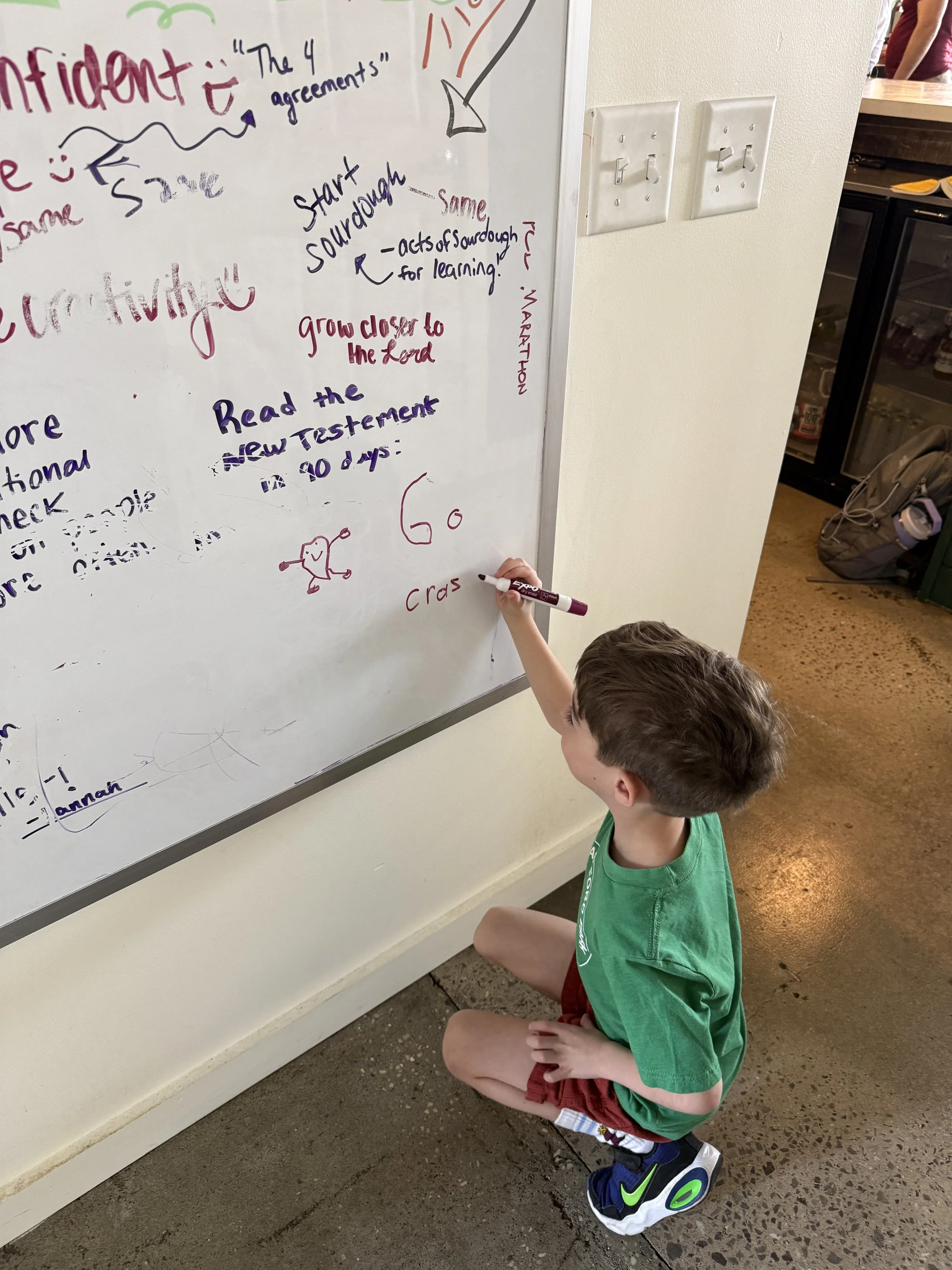 Young boy writing on vertical white board