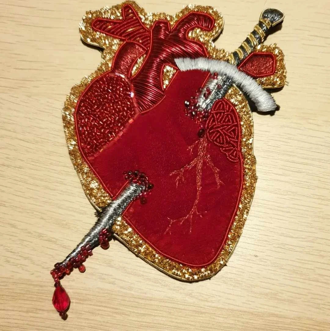 "Graceless Heart" goldwork embroidery, 2023. Padded velvet embroidered with goldwork bullion, metallic thread, and glass and garnet beads.