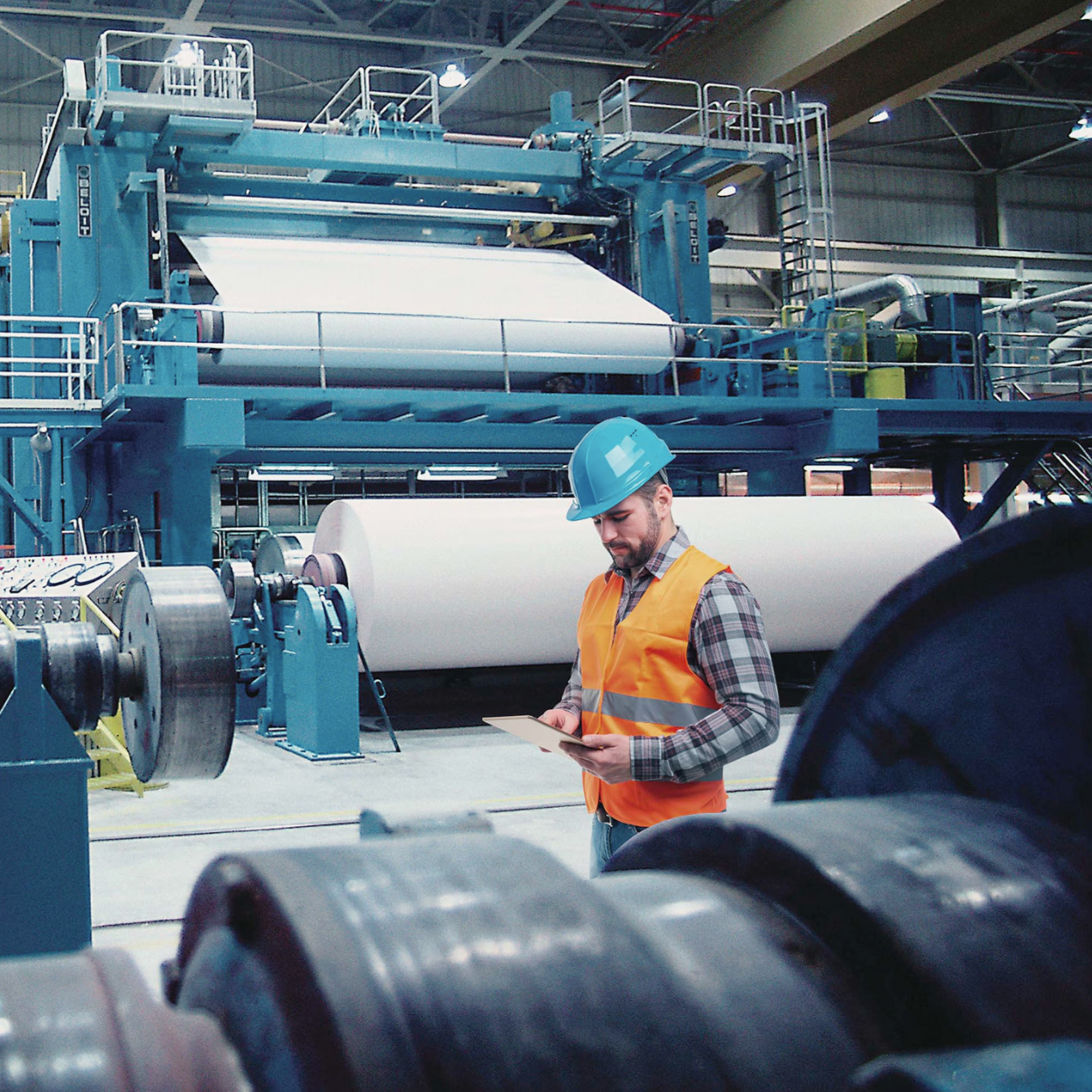 Pulp and paper manufacturing facility with technician inspecting equipment, representing quality control and operational oversight.