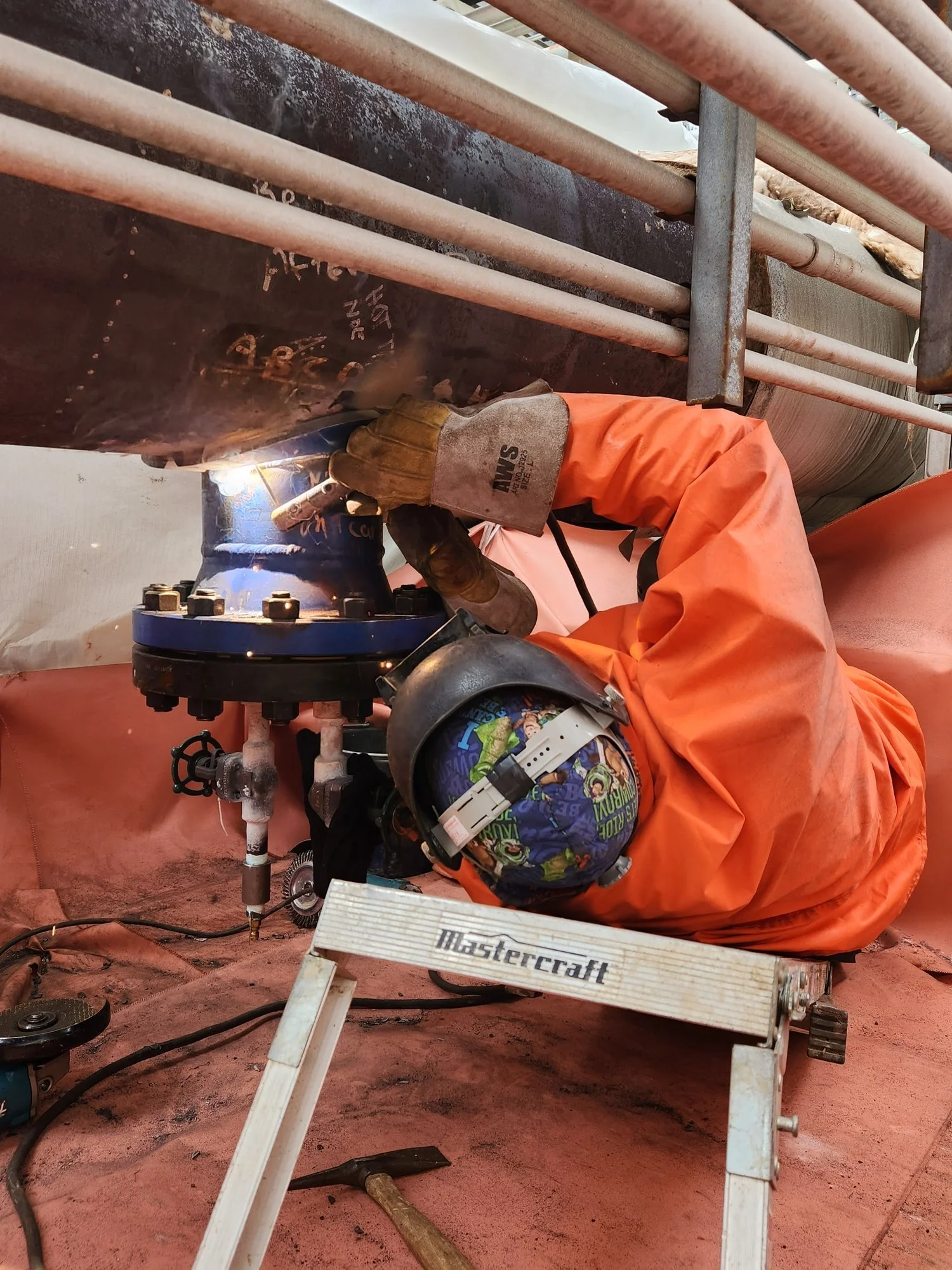 Certified welder performing a hot tap on an active pipeline during an industrial line intervention, with quality and safety oversight in place.