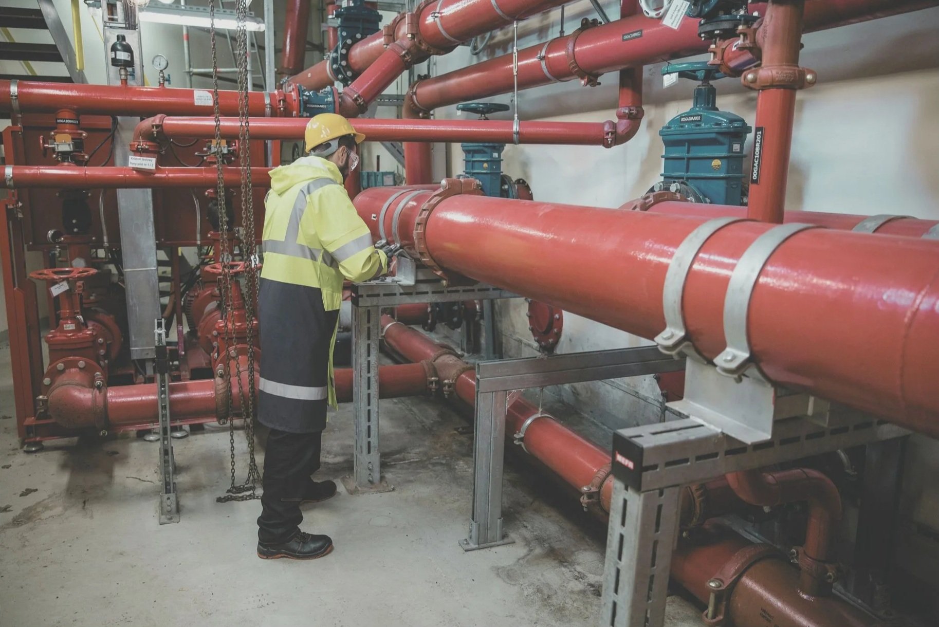 Technician inspecting industrial piping and equipment, representing proactive asset integrity inspection to prevent unplanned equipment failures.