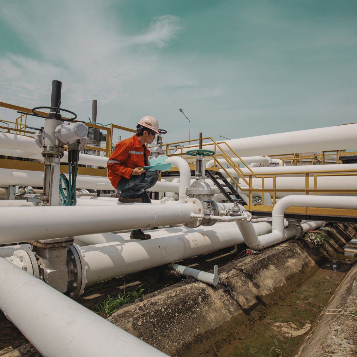 Industrial pipeline infrastructure with field technician inspecting piping systems for quality, safety, and asset integrity compliance.