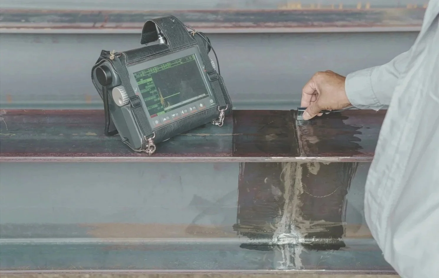 Technician using ultrasonic testing equipment on a weld seam.