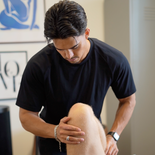 Physical therapist examining a patient's knee in a clinic.