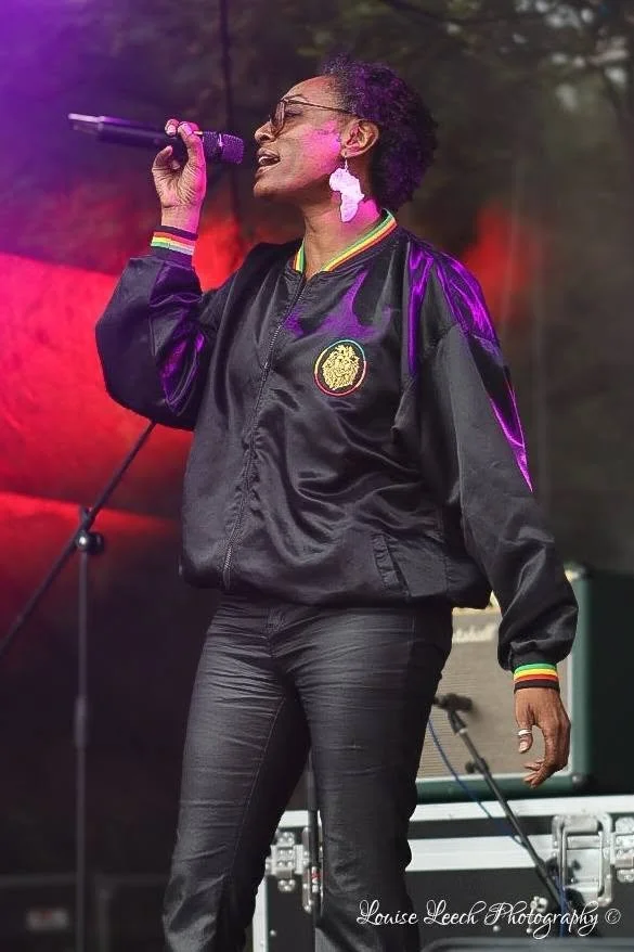 Image of Island Collective performing on stage, showing lead singer, Leoni..