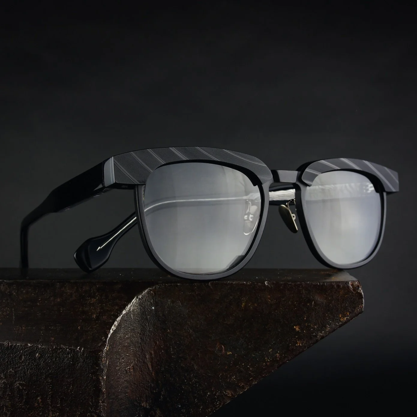 Black modern eyeglasses with reflective lenses on a dark surface.