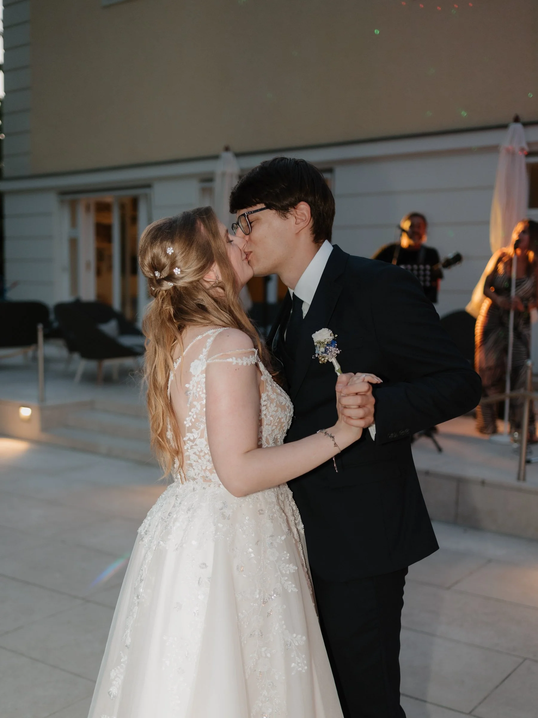 Ein Brautpaar küsst sich bei einer Hochzeit im Freien mit Live-Musik im Hintergrund.