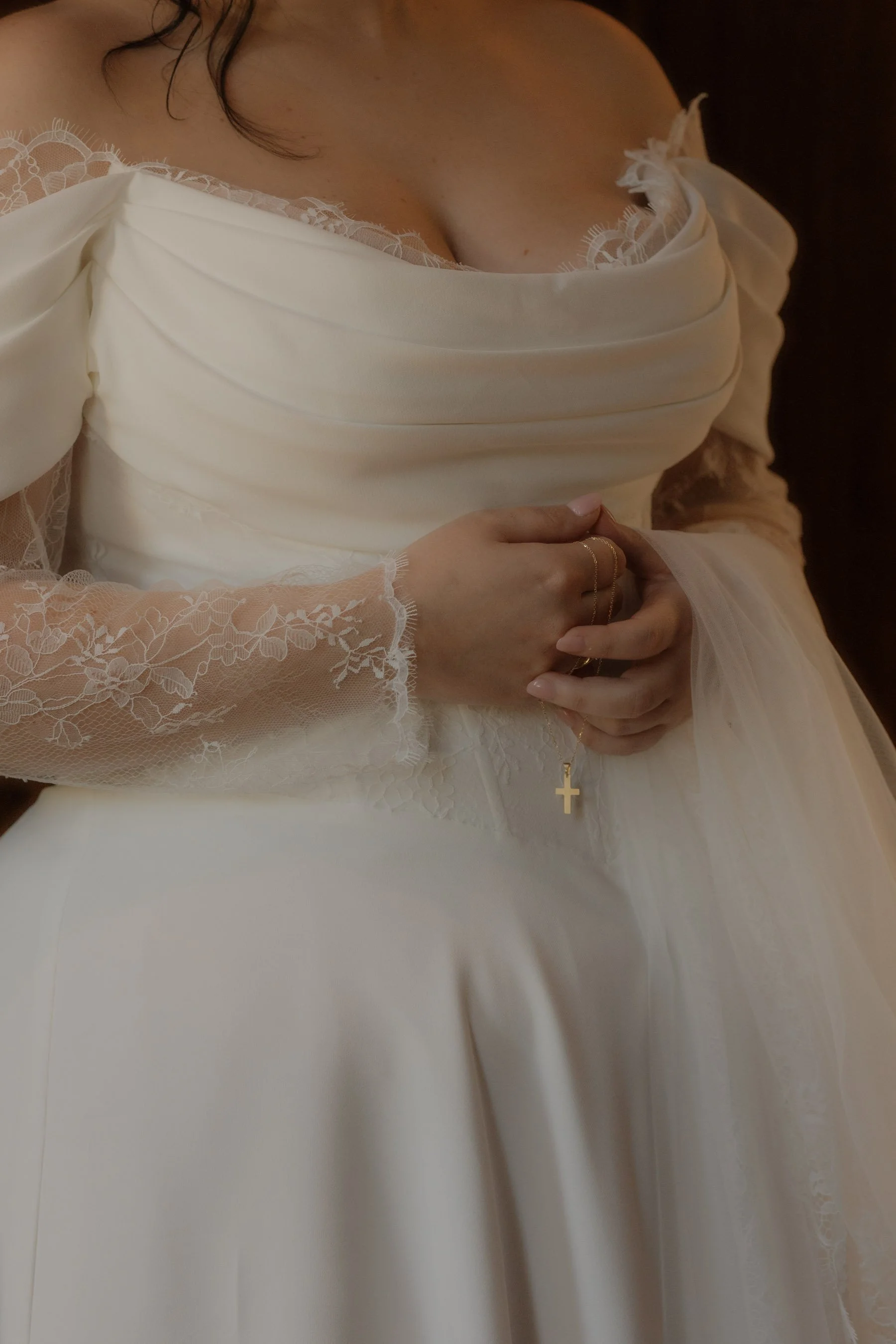Detailaufnahmen, Hochzeit, Glauben. Christliche Hochzeit. Nahaufnahme eines Frauenoberkörpers in einem weißen Kleid mit Spitze und einer goldenen Kettenkreuz-Halskette.
