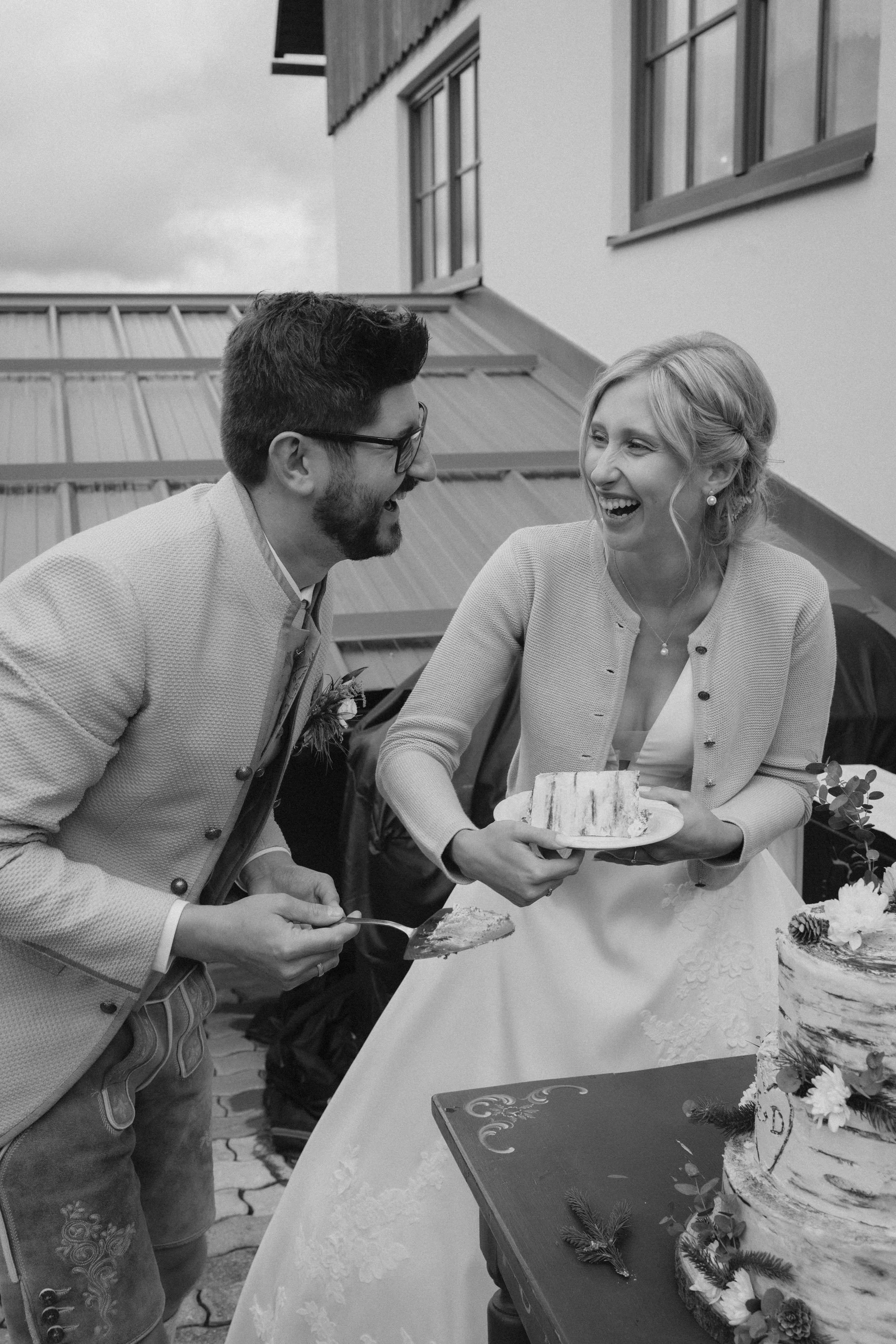 Ein Mann und eine Frau bei einer Feier, lachen und teilen ein Stück Kuchen.