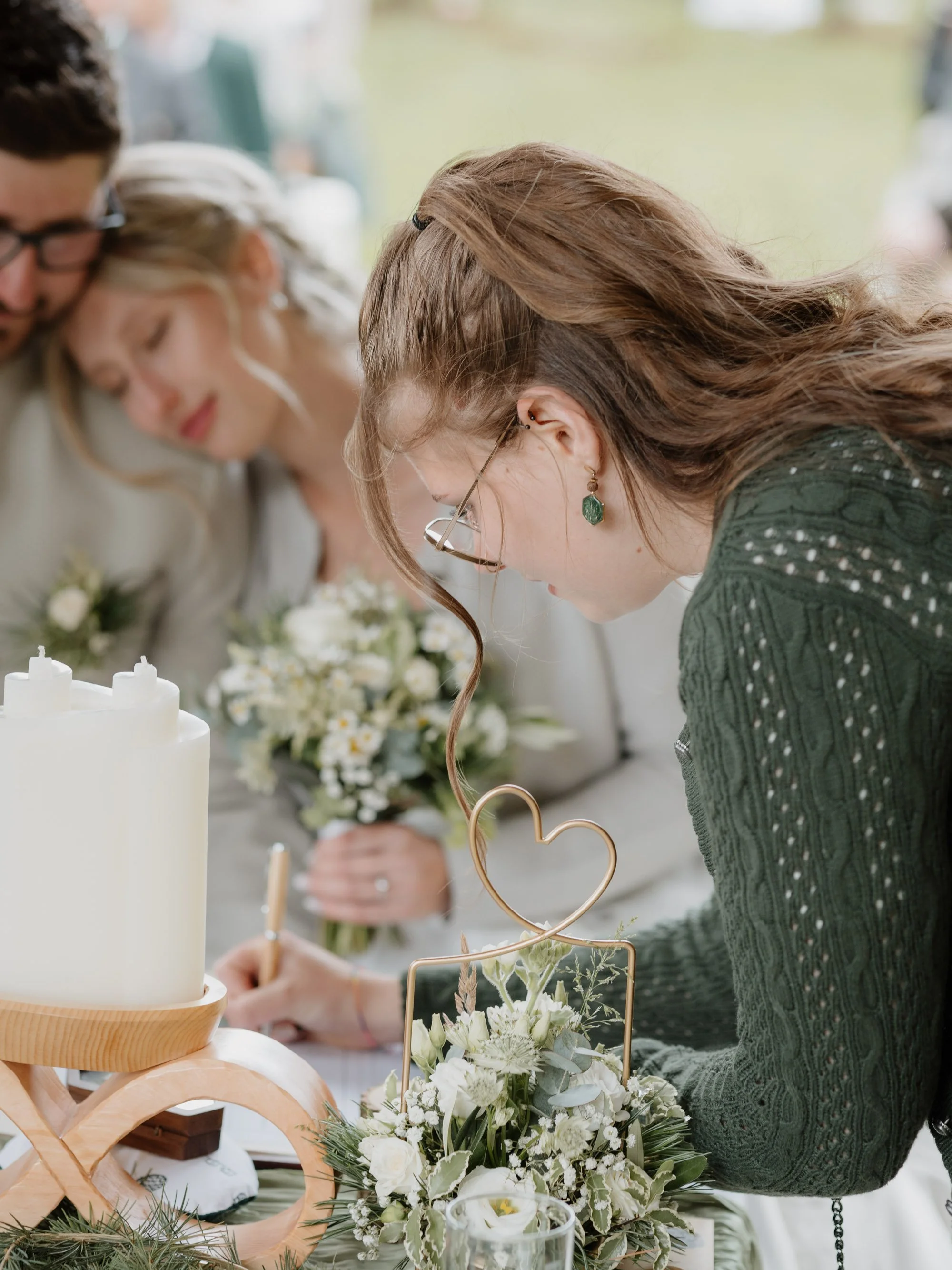 Menschen beim Dekorieren eines Hochzeitstisches mit weißen Blumen und Kerzen, im Hintergrund ein weißer Hochzeitstorte