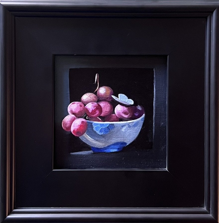 Painting of a bowl of purple grapes in a frame.