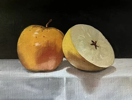 An apple and a sliced pear on a white surface with a dark background.