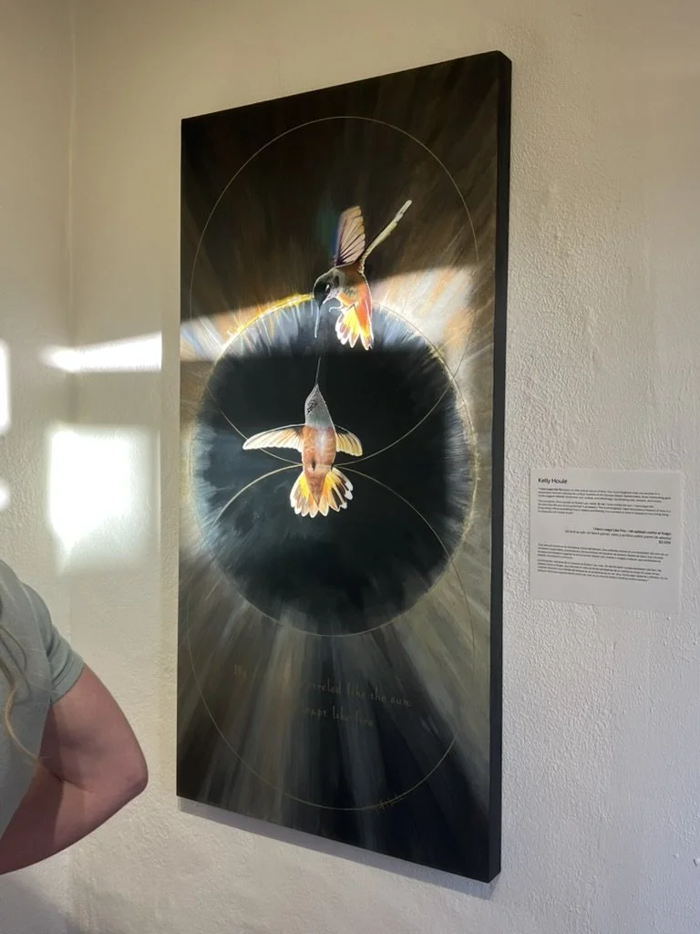 A painting of two hummingbirds flying towards each other, set against a dark, circular background with light rays and geometric circles.