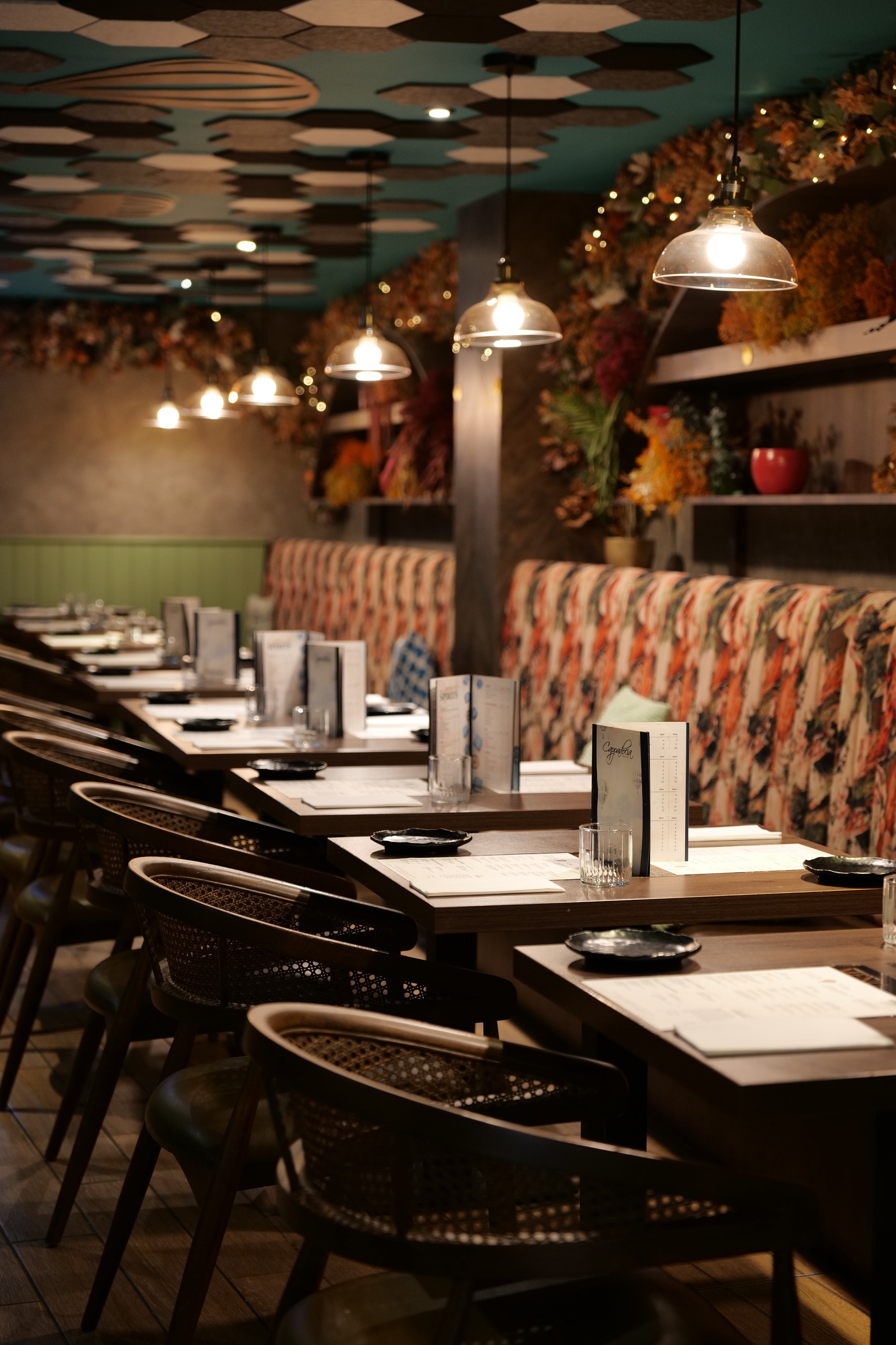 Photography restaurant content showing an empty Bristol restaurant with tables set for dine-in, decorated with menus, plates, glasses, and black dishes, featuring floral wall decorations and modern hanging lights.