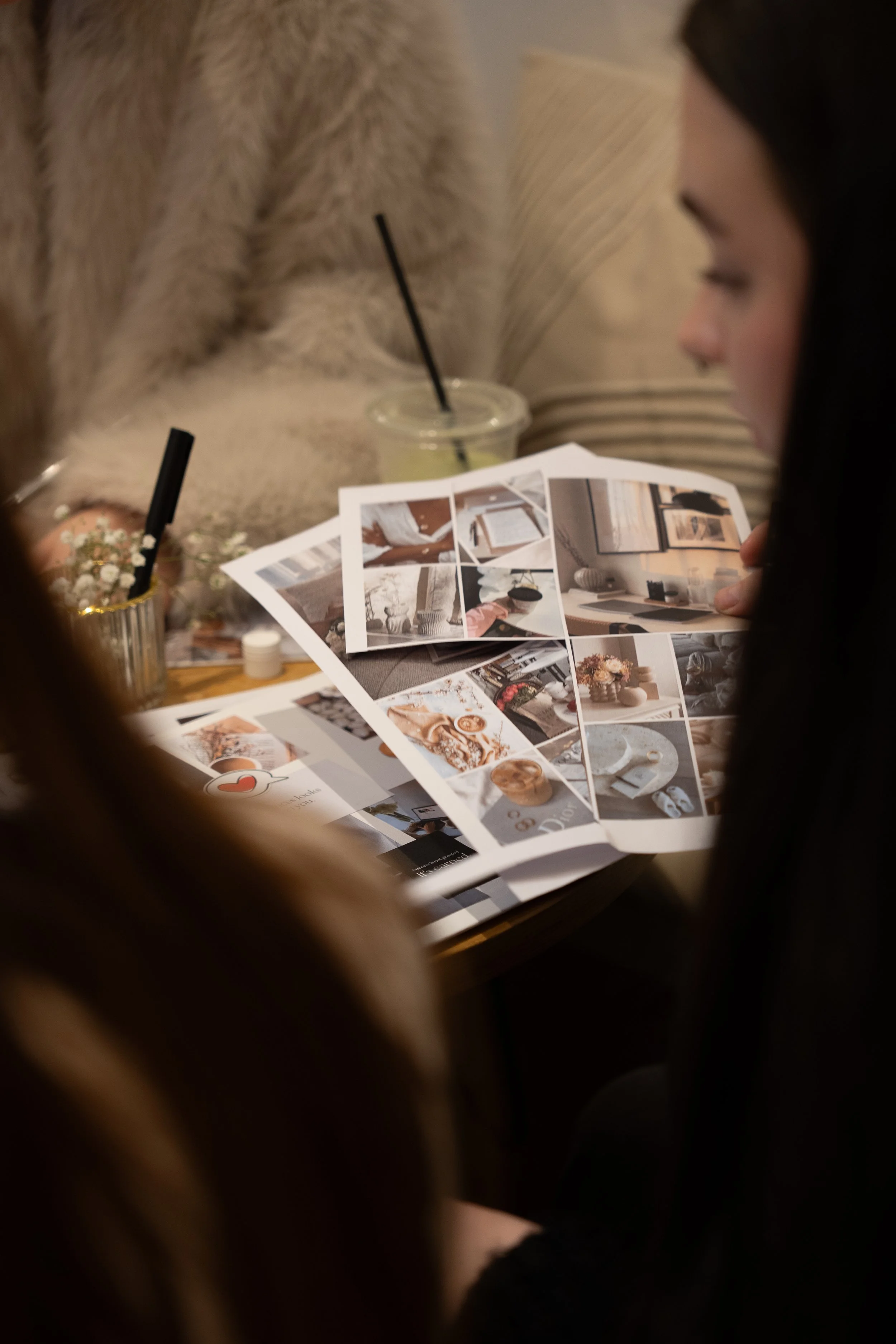 Photography cafe content showing two women sitting at a table looking at interior design magazines in a cozy setting.