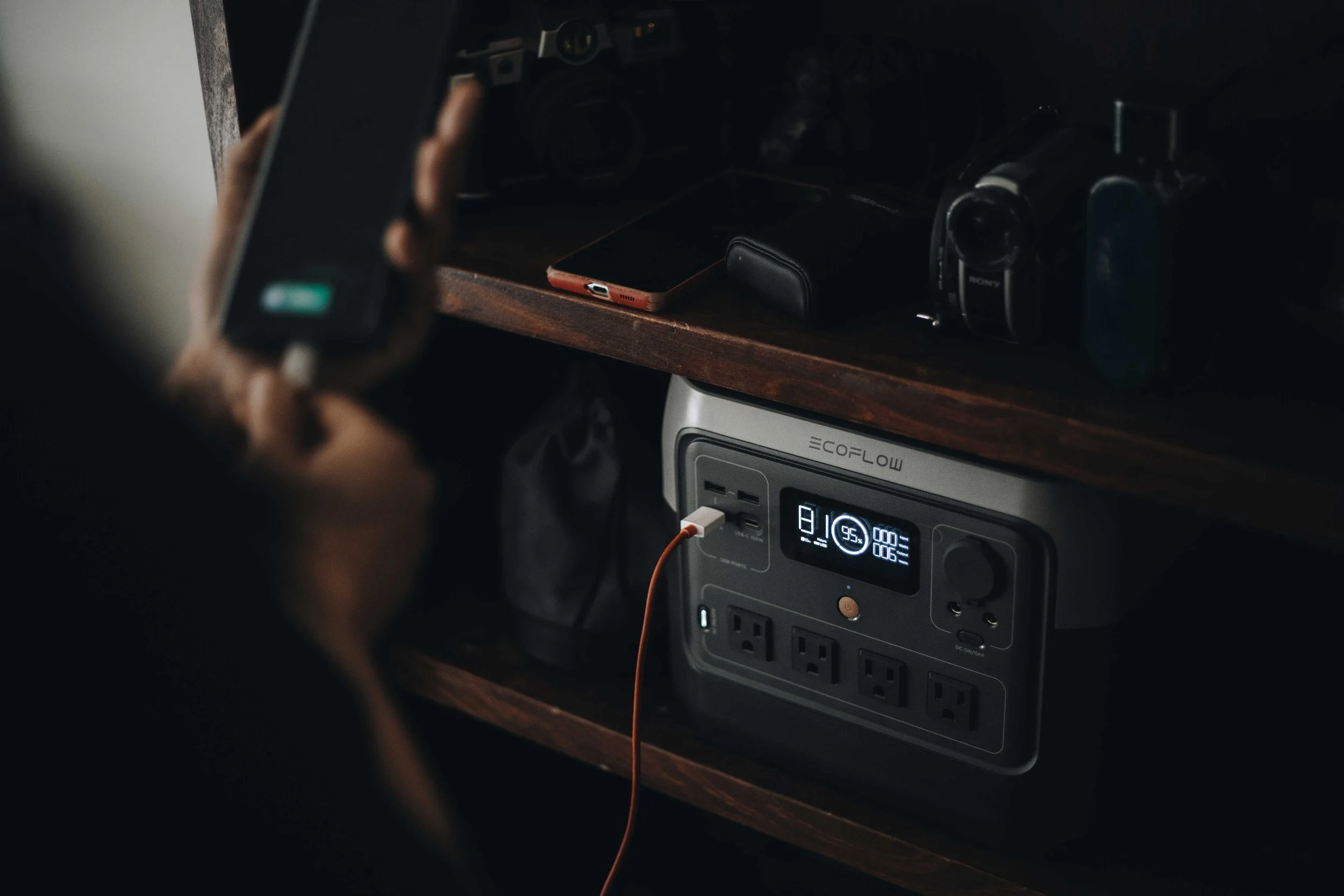 Fotografía lifestyle EcoFlow, estación de energía portátil cargando dispositivos en interior oscuro