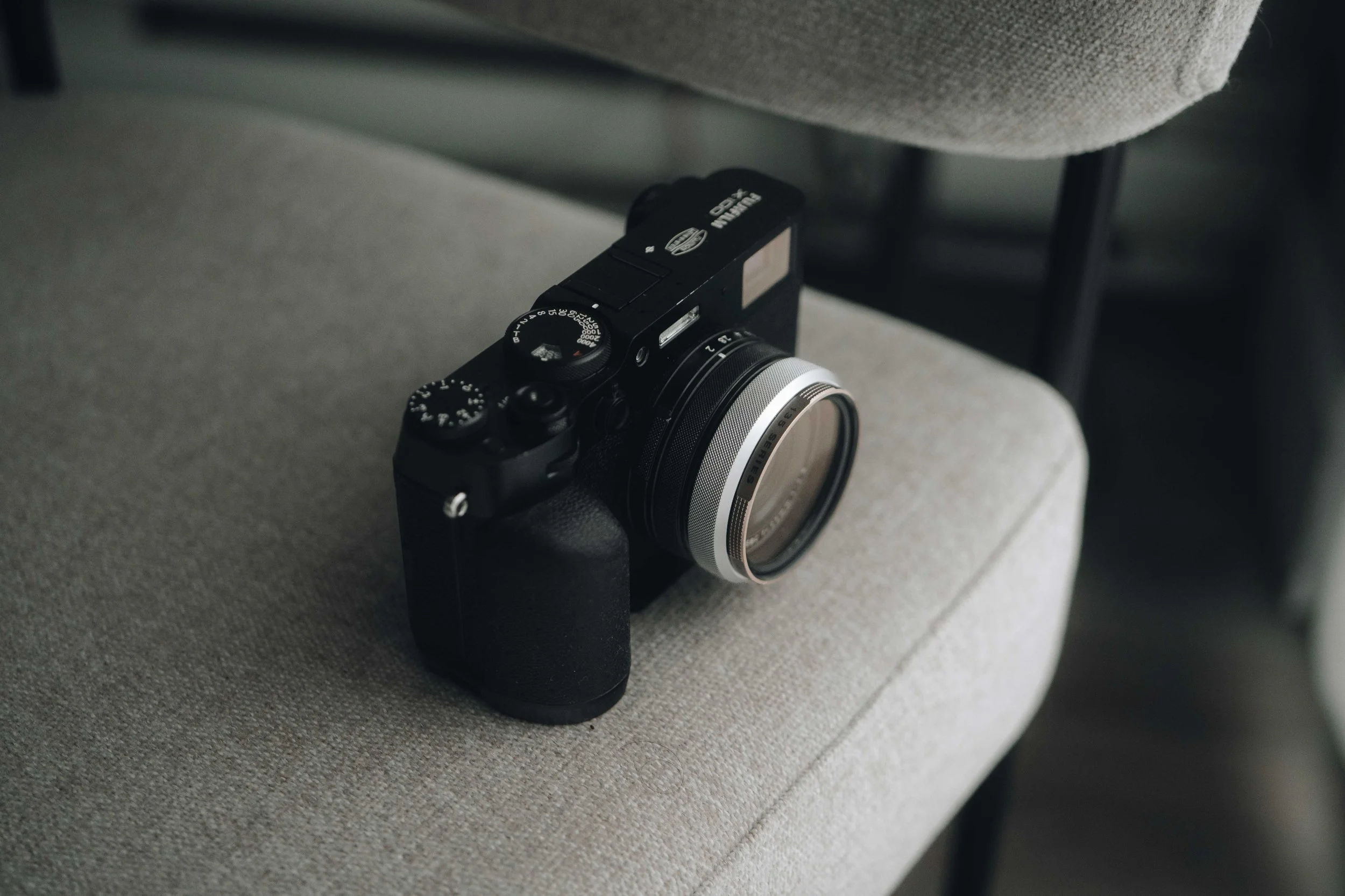 Fotografía de producto Fujifilm X100VI, cámara compacta negra sobre sofá