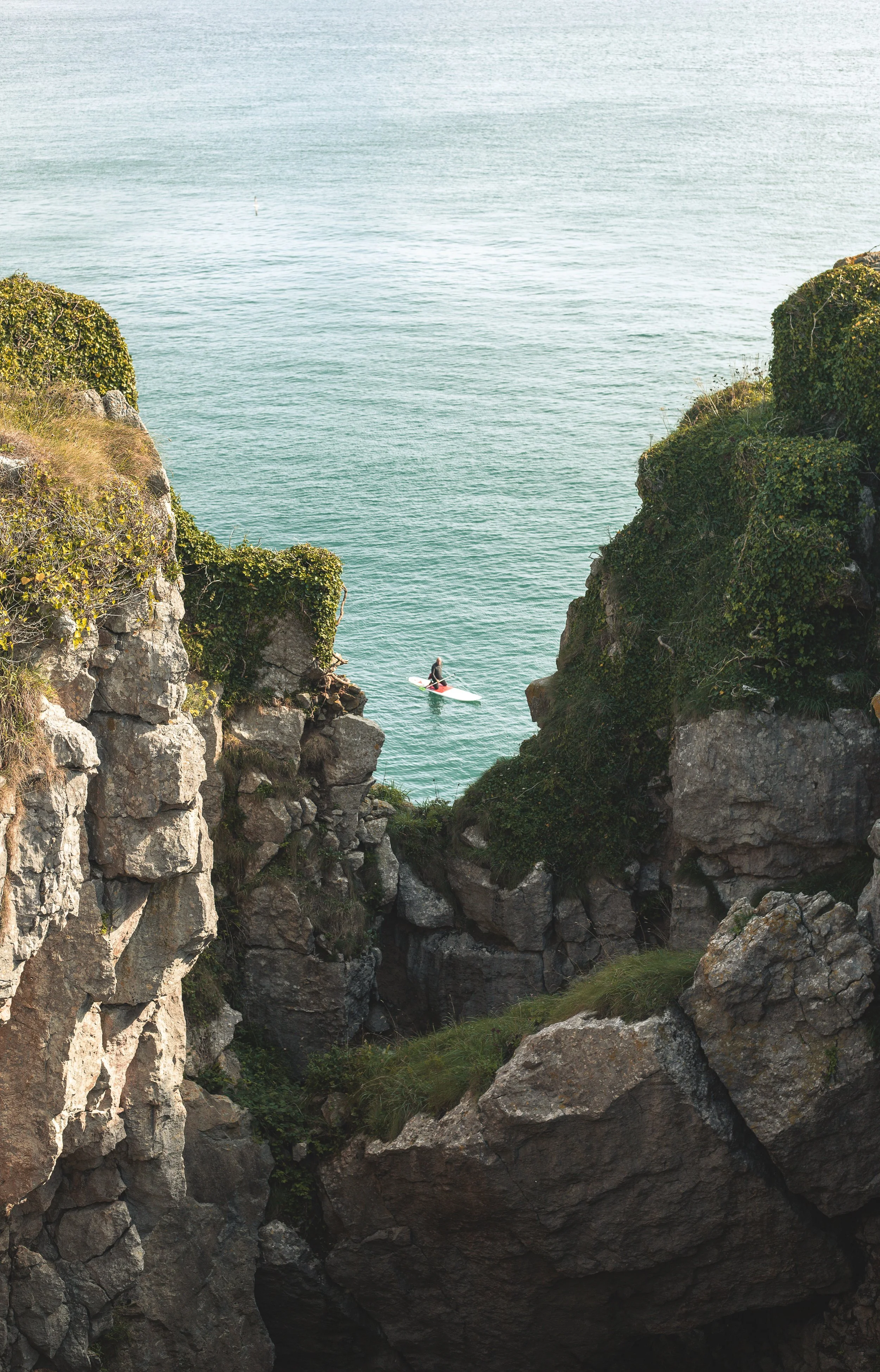 A person surfing between rocky cliffs on the ocean.