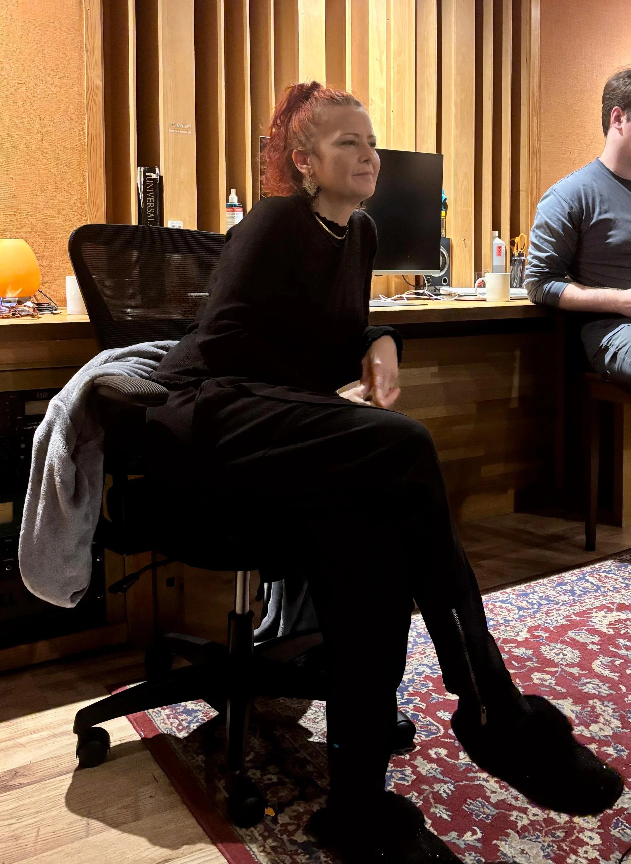 Cool lady in cozy room, laughing and smiling, with one person touching another's shoulder.