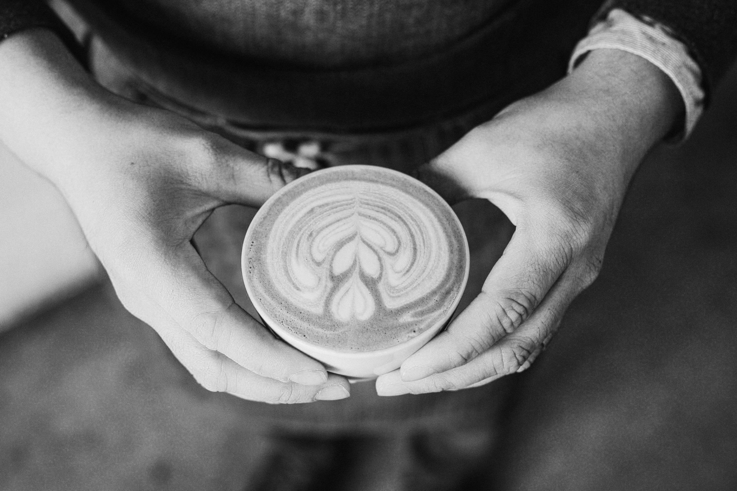 Person holding a cup of coffee with latte art