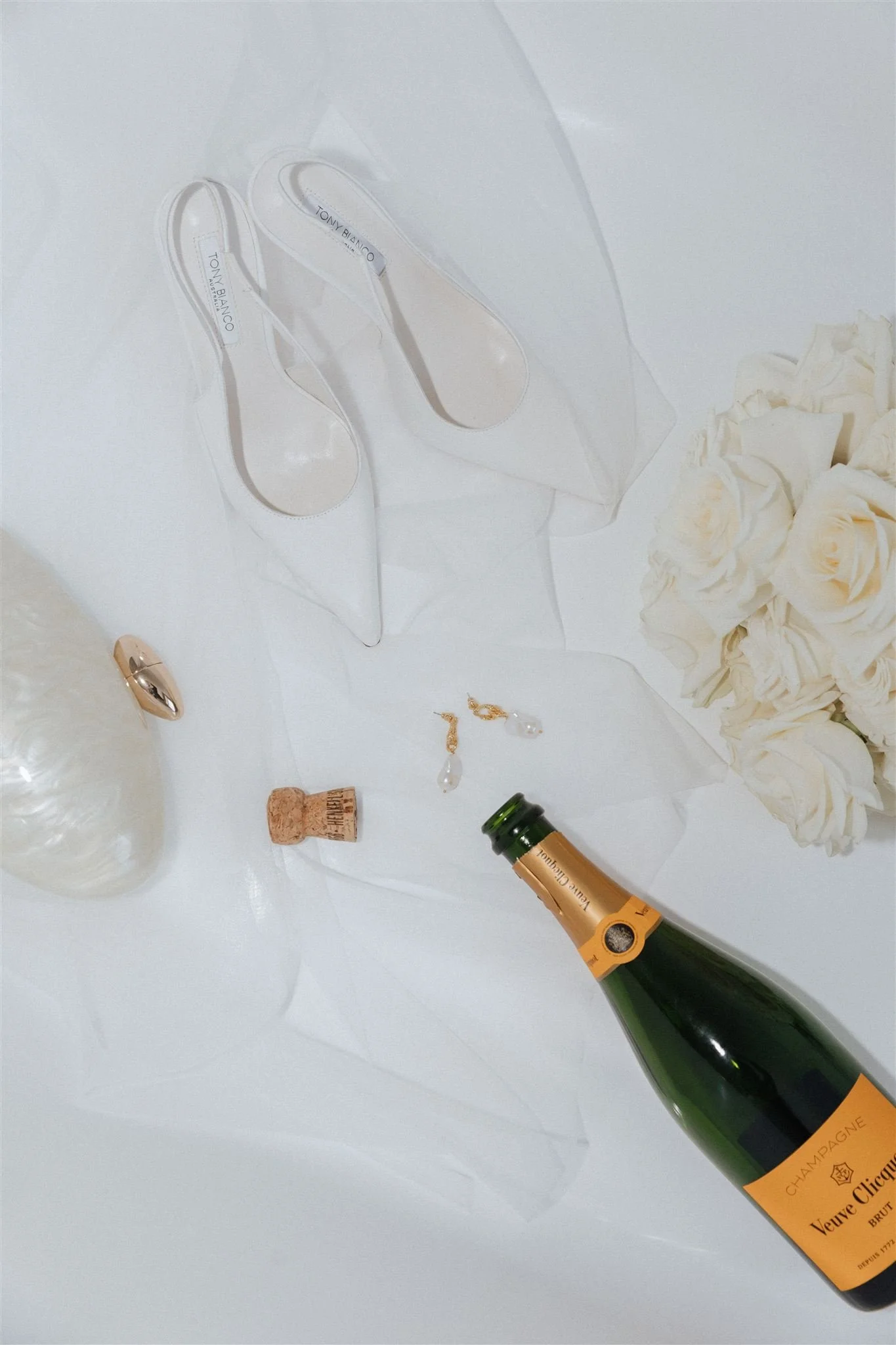 Black and white image of a long dining table set with wine glasses, napkins, cutlery, and a centerpiece of leaves running along the middle.