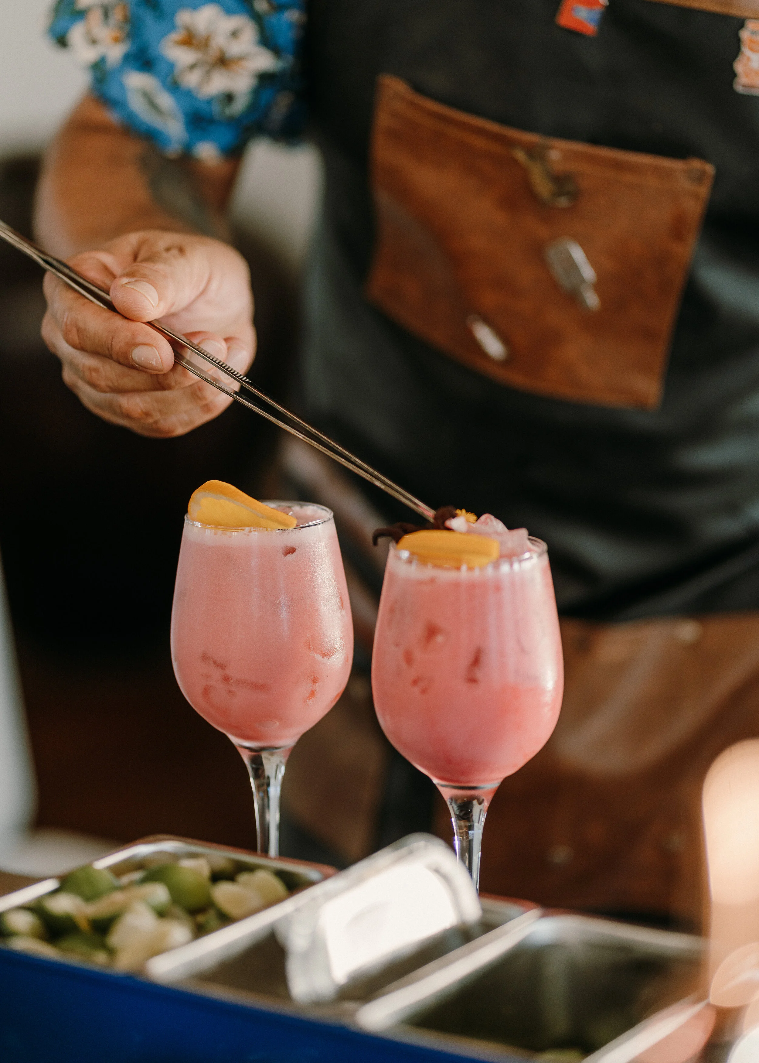 Bartender adding custom premium garnishes to multiple glasses