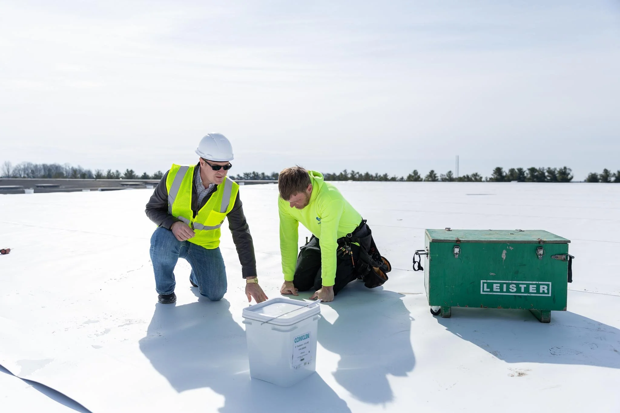 Commercial roofing contractors installing reflective white roof restoration system on flat roof in Indiana