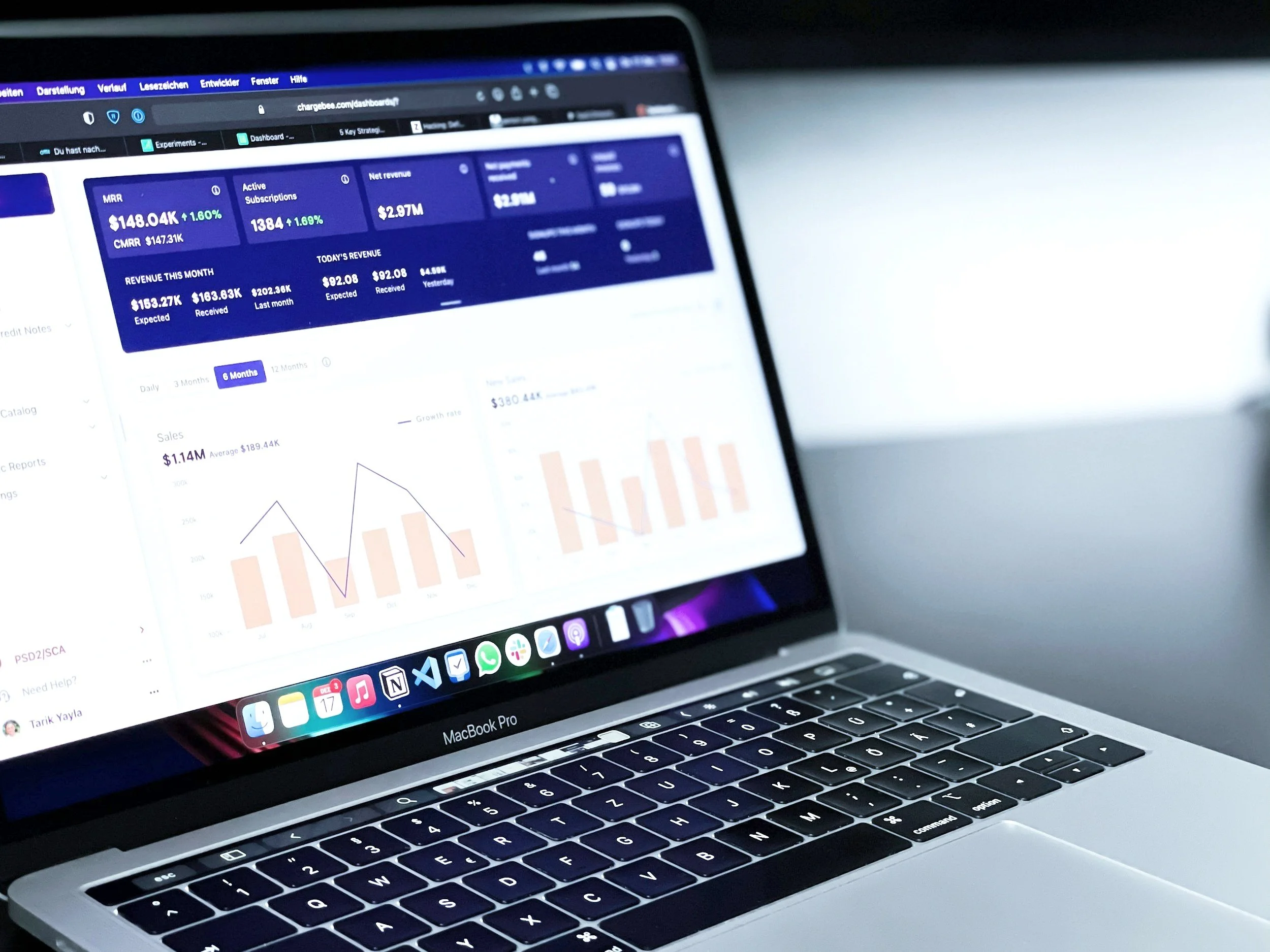 Open MacBook Pro displaying a financial dashboard with charts, graphs, and revenue data.