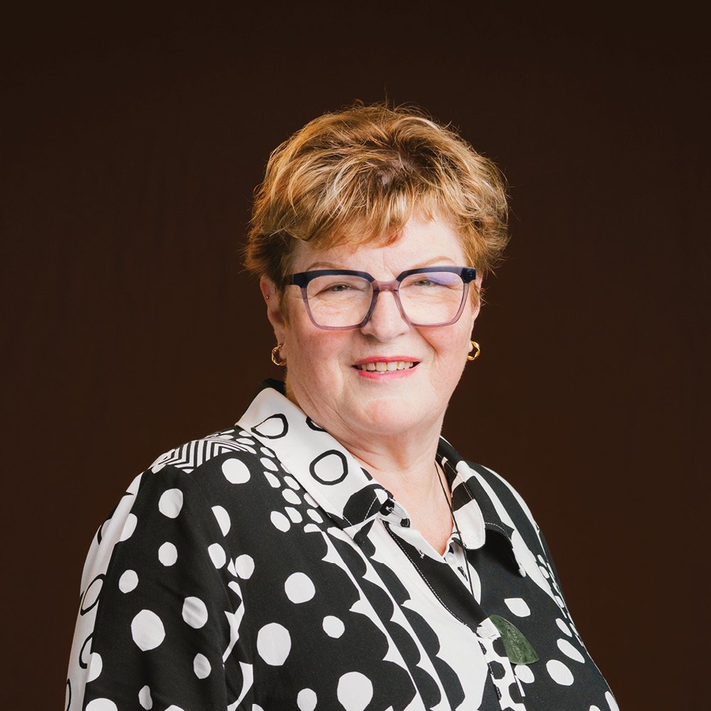Person wearing glasses and a striped shirt against a dark background.