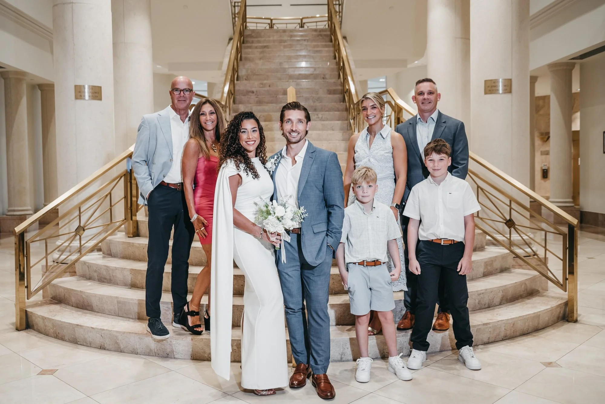 Bride and groom with their family on the grand staircase at the Delray Beach courthouse