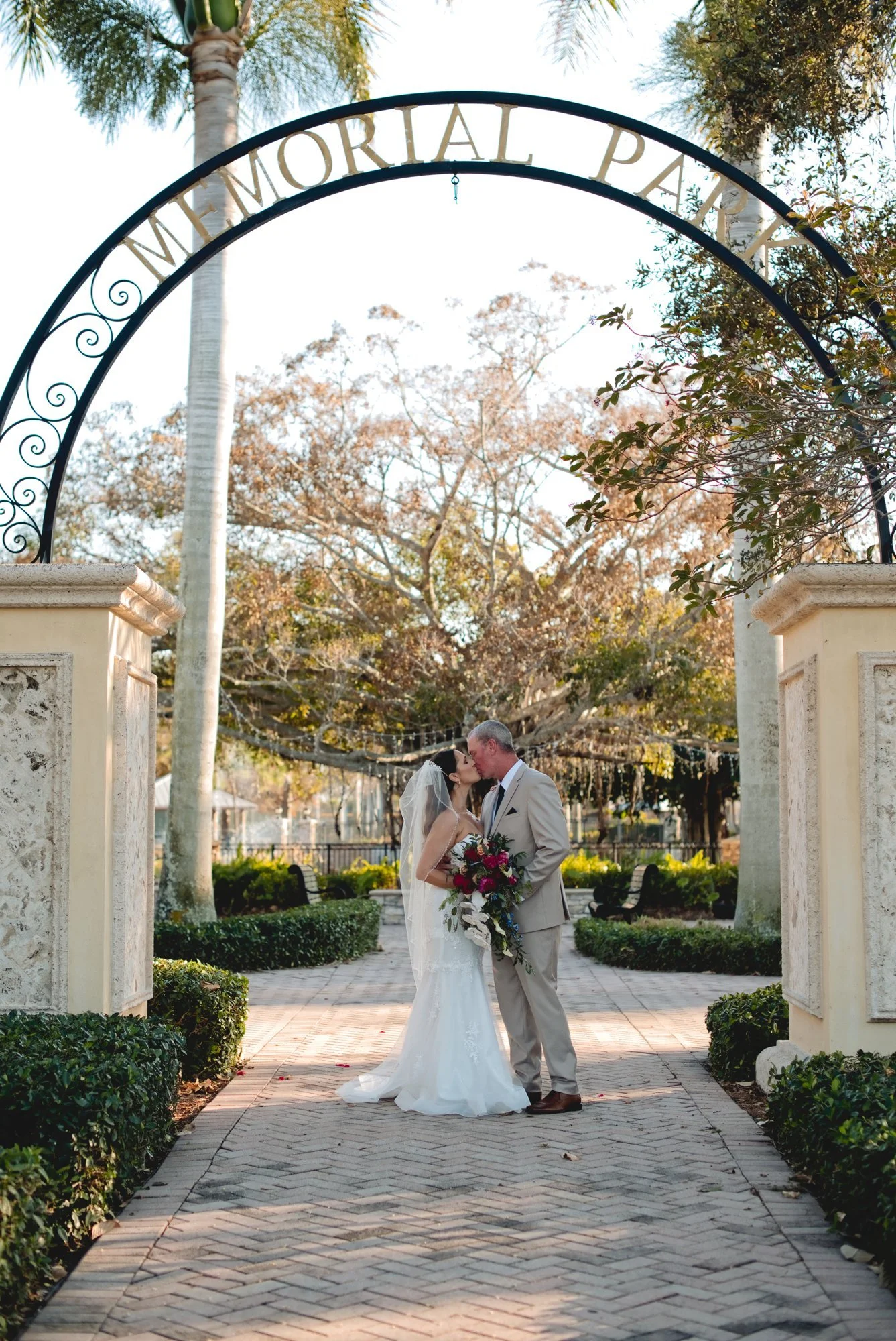 Bride and groom embracing beneath the Memorial Park arch in Stuart, Florida