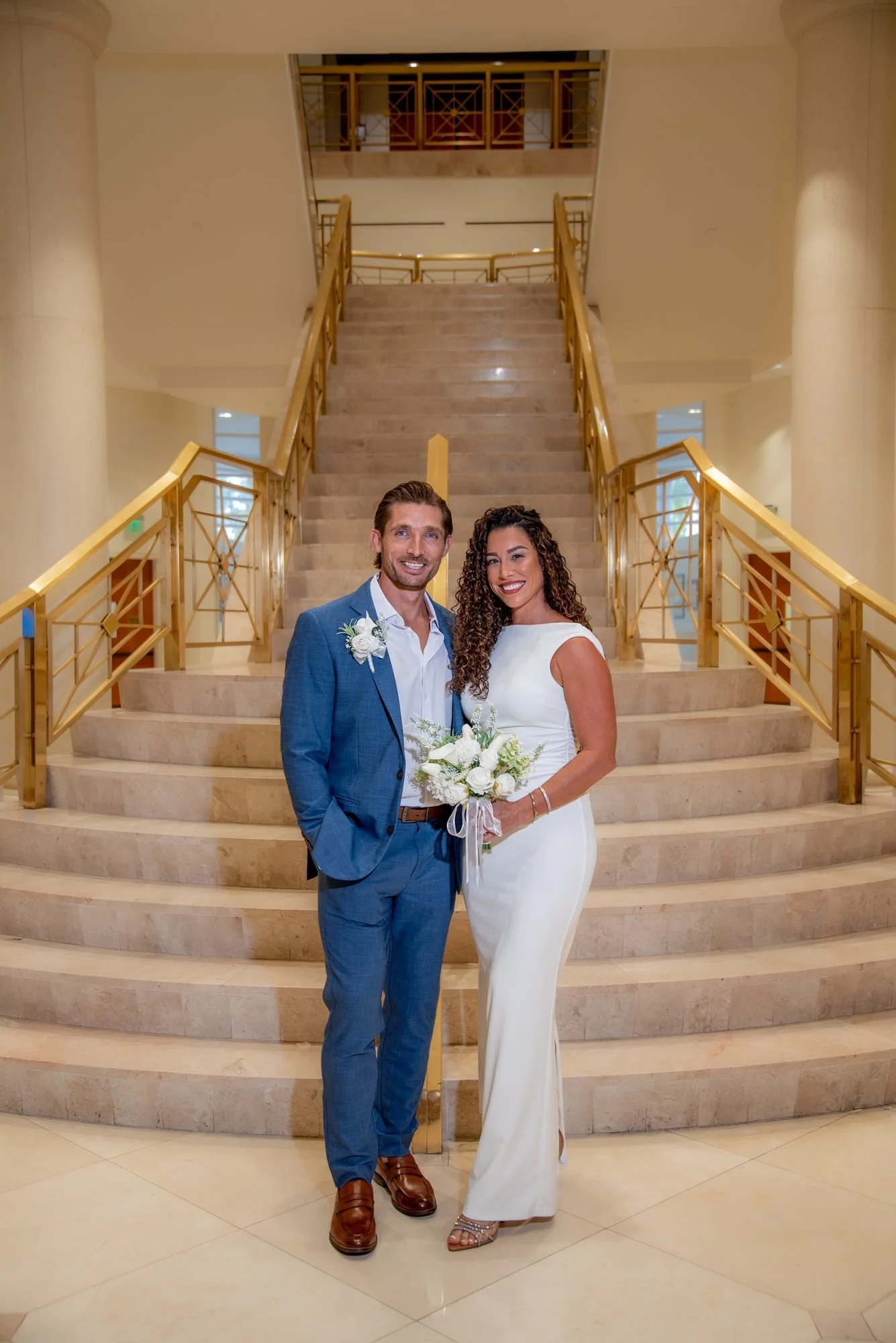 Bride and groom standing on the gold staircase inside the Delray Beach South County Courthouse