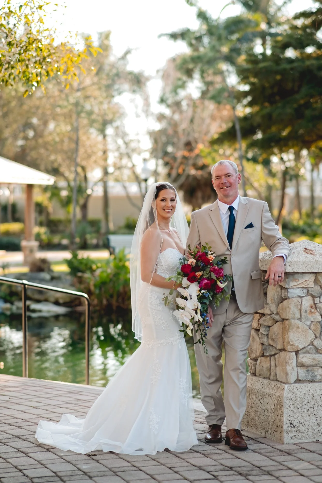 Bride and groom posing by a stone wall overlooking the water in Stuart