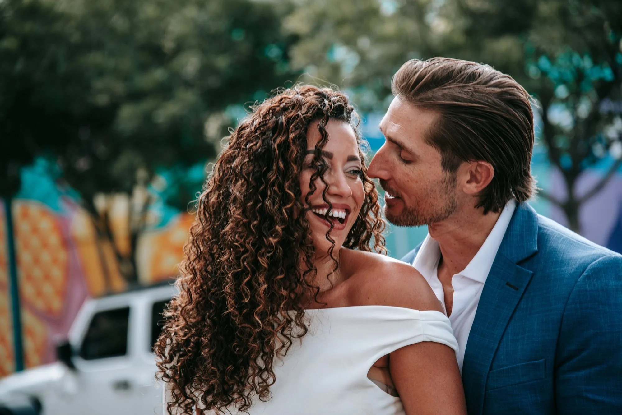 Close-up of a bride laughing as her new husband kisses her cheek in Pineapple Grove, Delray Beach