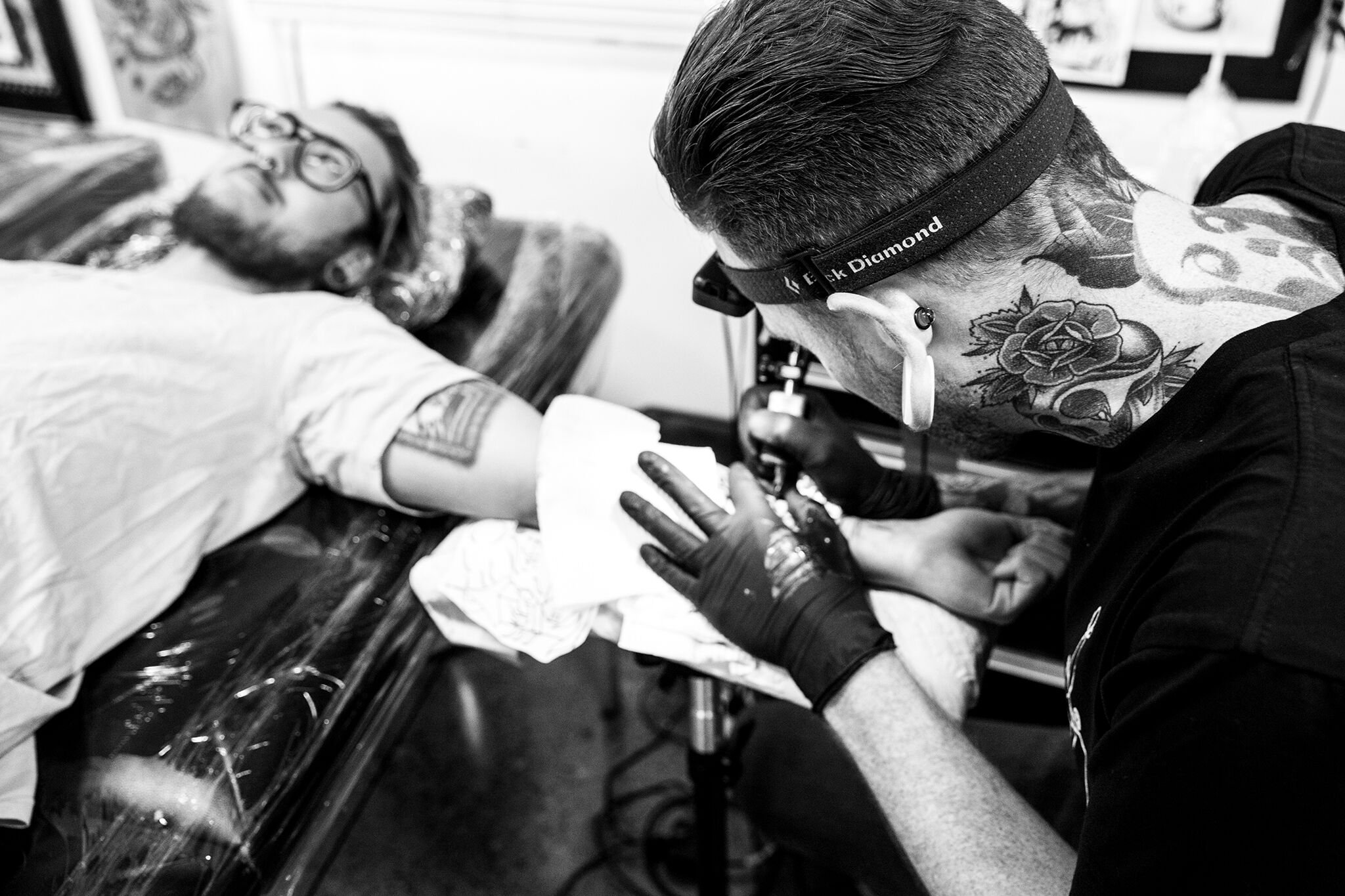 Tattoo artist working on a tattoo on a person's arm in a tattoo studio.