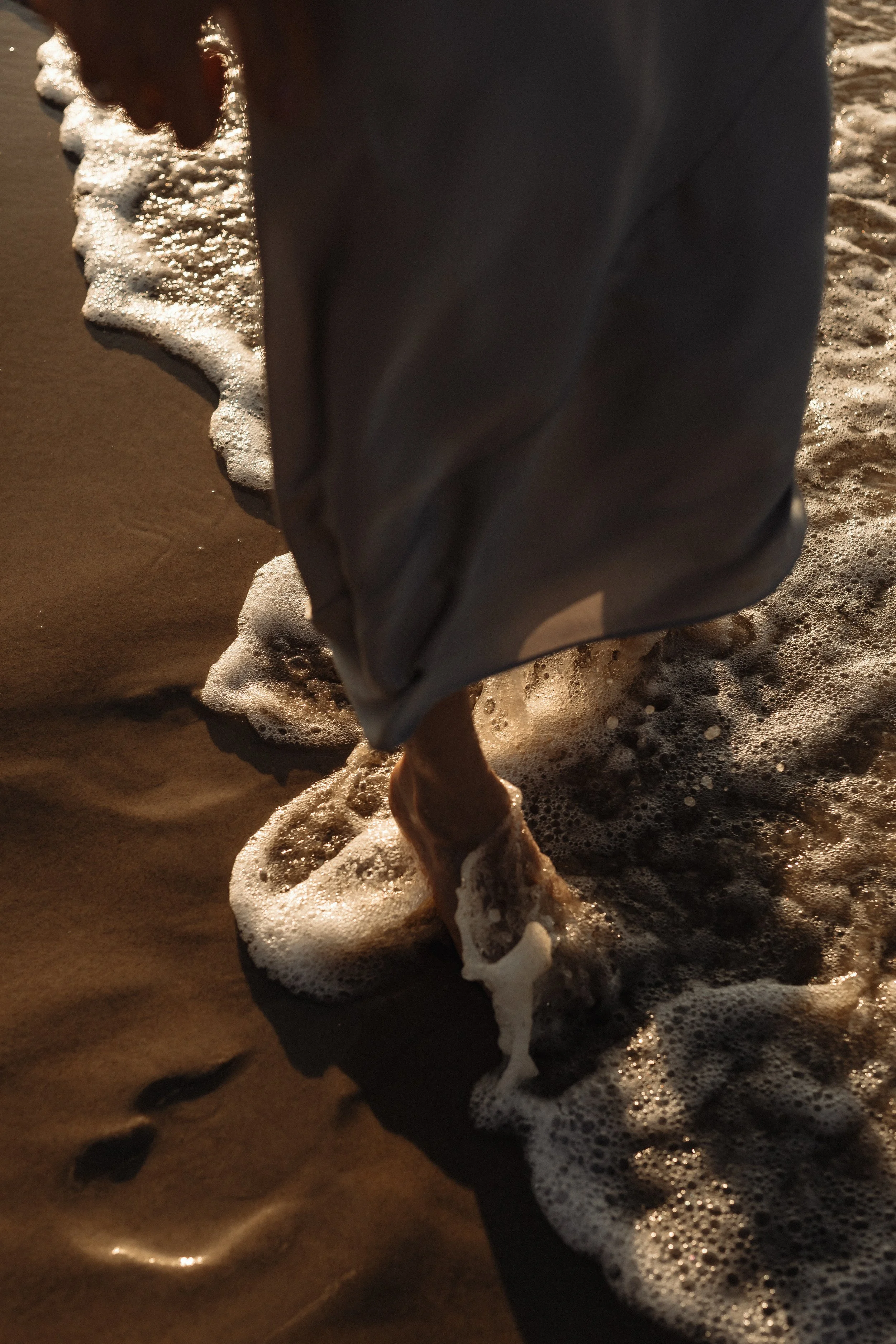Bare feet standing in ocean waves, grounding back into the body
