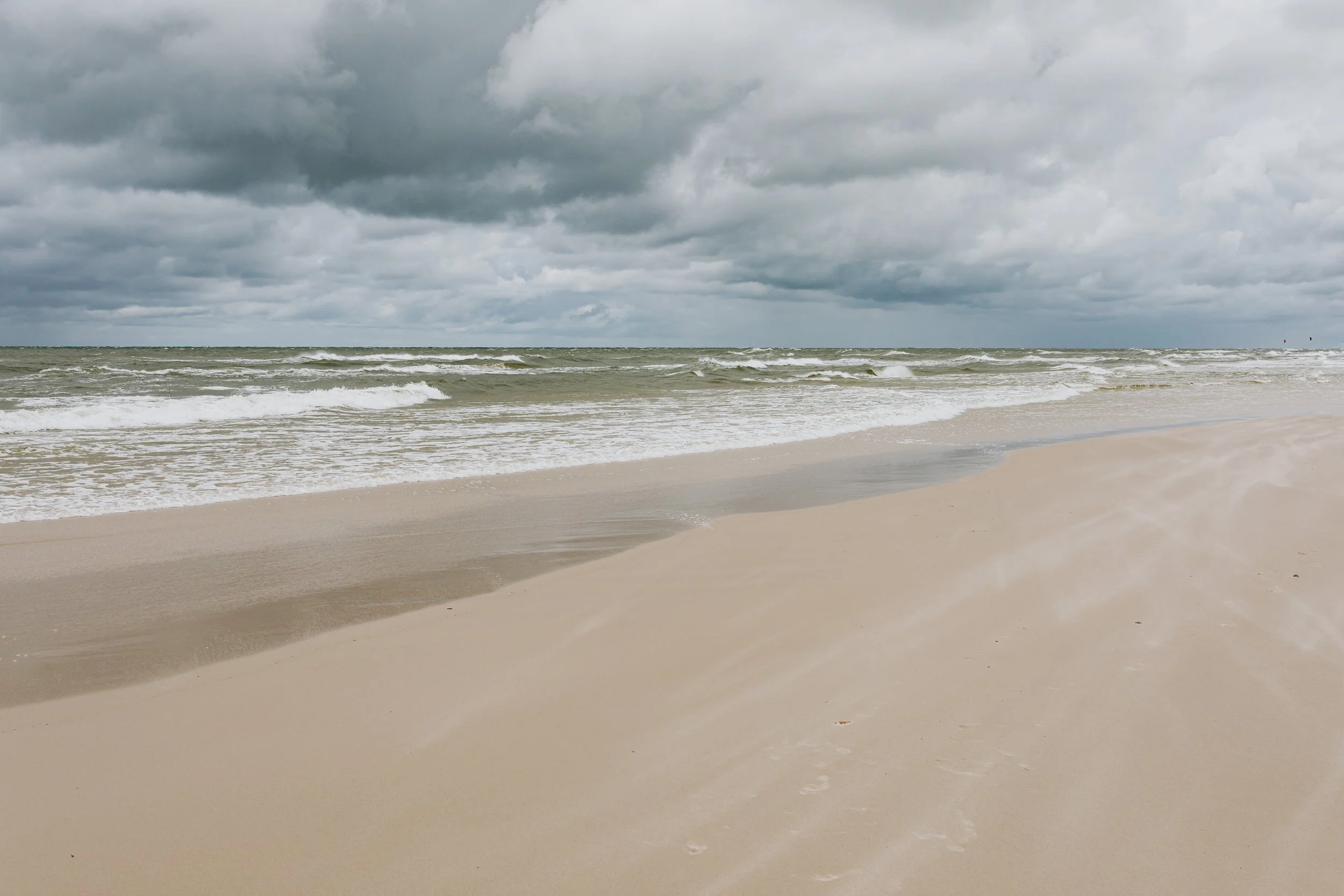 Calm, empty beach shoreline under a cloudy sky