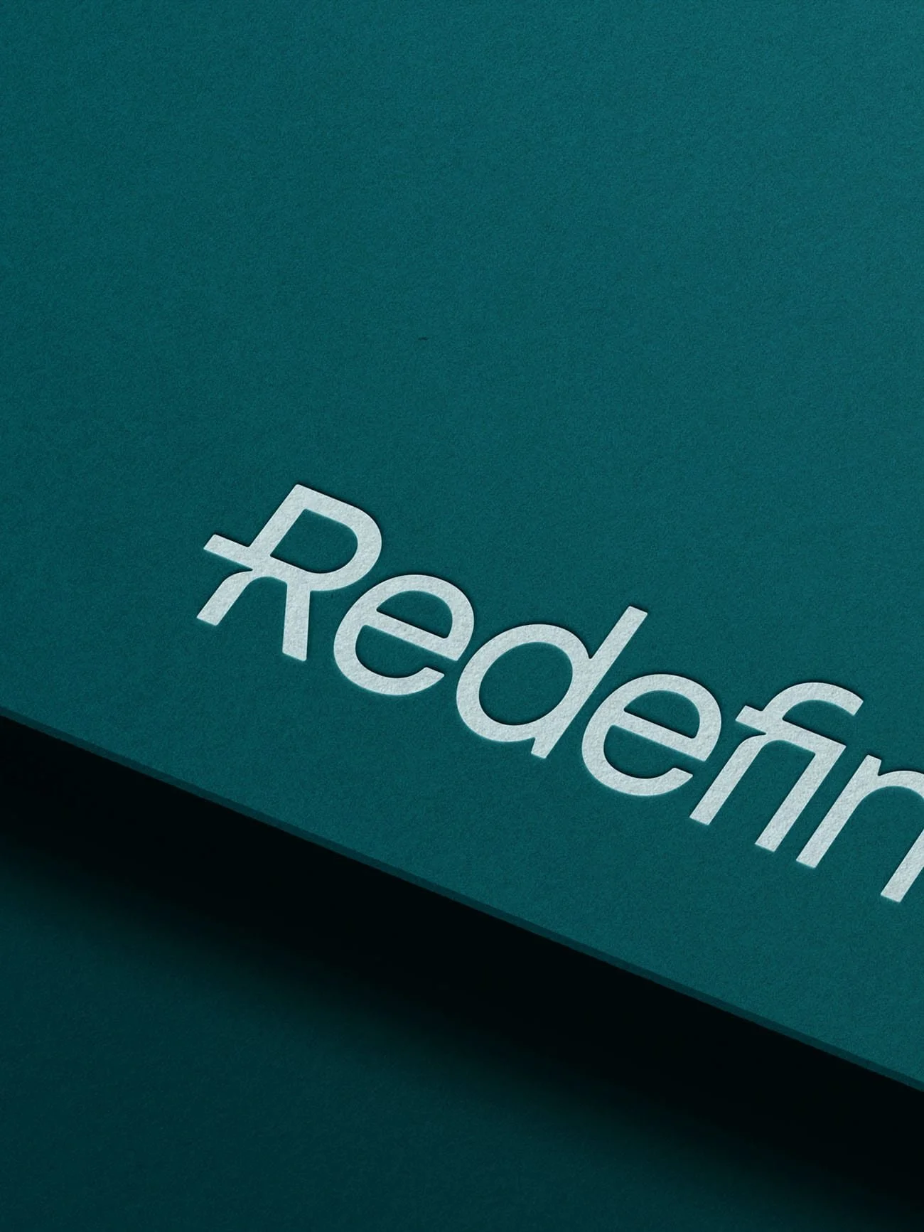 Branding design for Redefine HR, a HR consulting firm, showing a light teal logotype embossed on a deep teal thick paper card stock