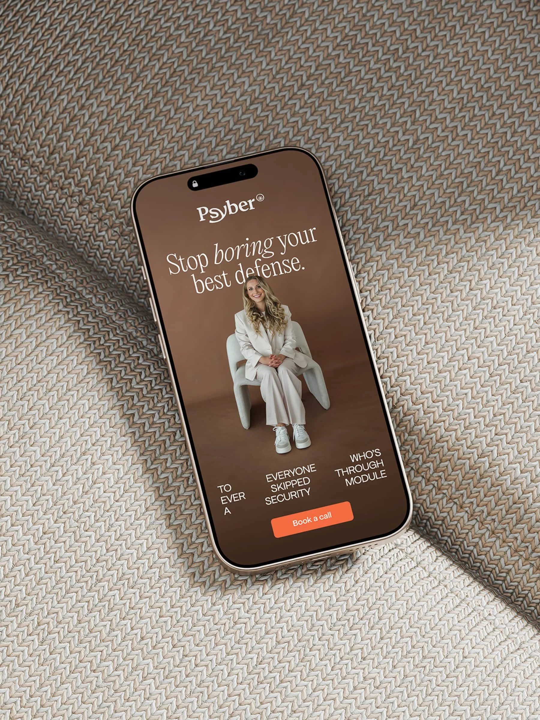Smartphone displaying the website design of Psyber — a cyber security consultant — with the text "Stop boring your best defense". A person is shown seated on a chair.