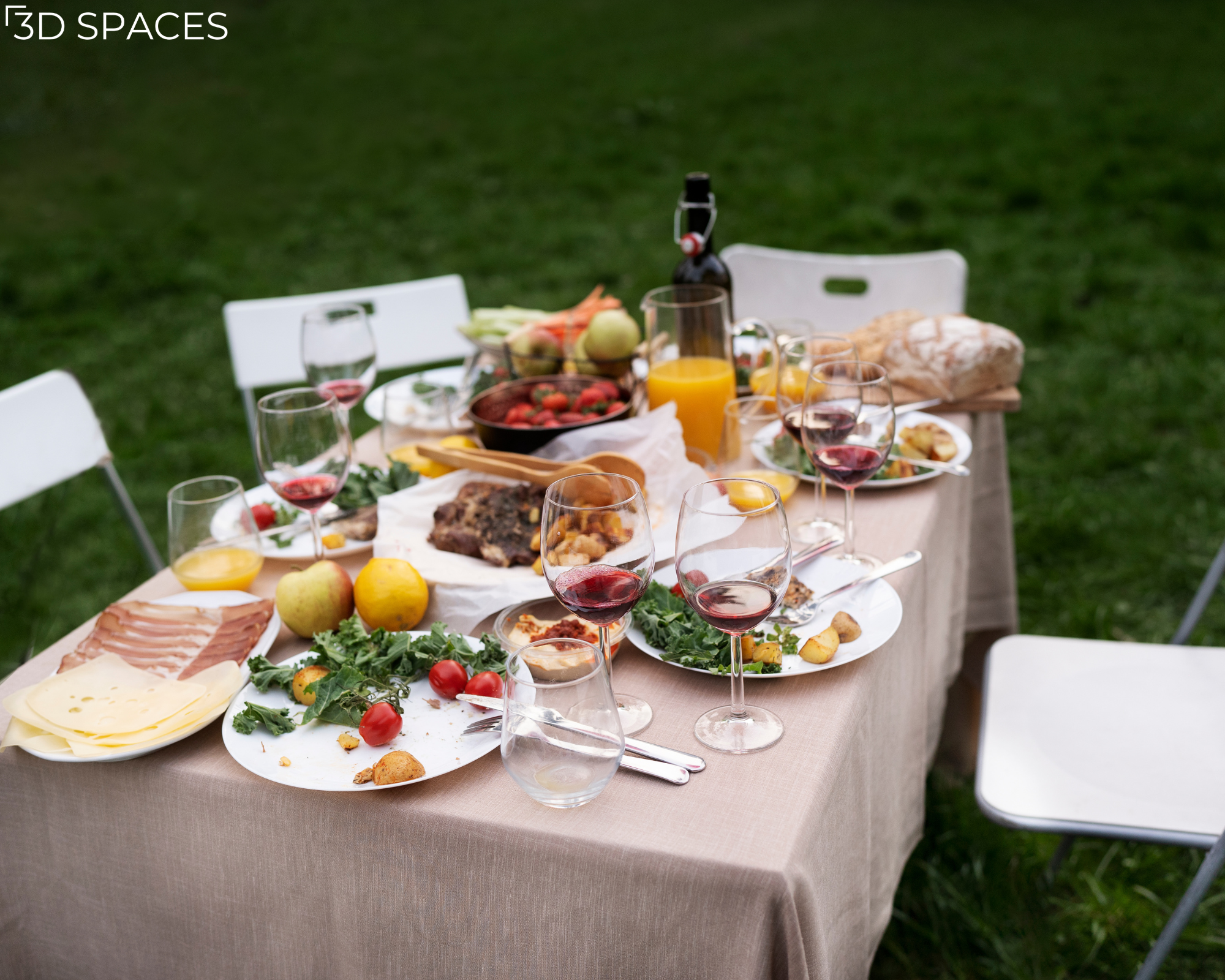 Al fresco dining spread featuring a catered meal with wine glasses, fresh fruit, cheese, and juices in a garden setting.