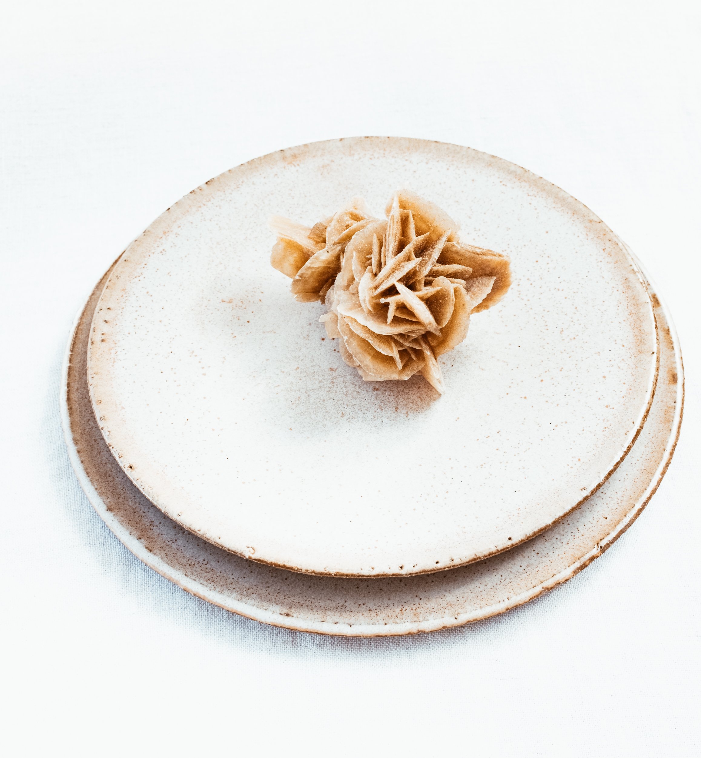 Decorative wood shavings arranged on a ceramic plate set against a white background.