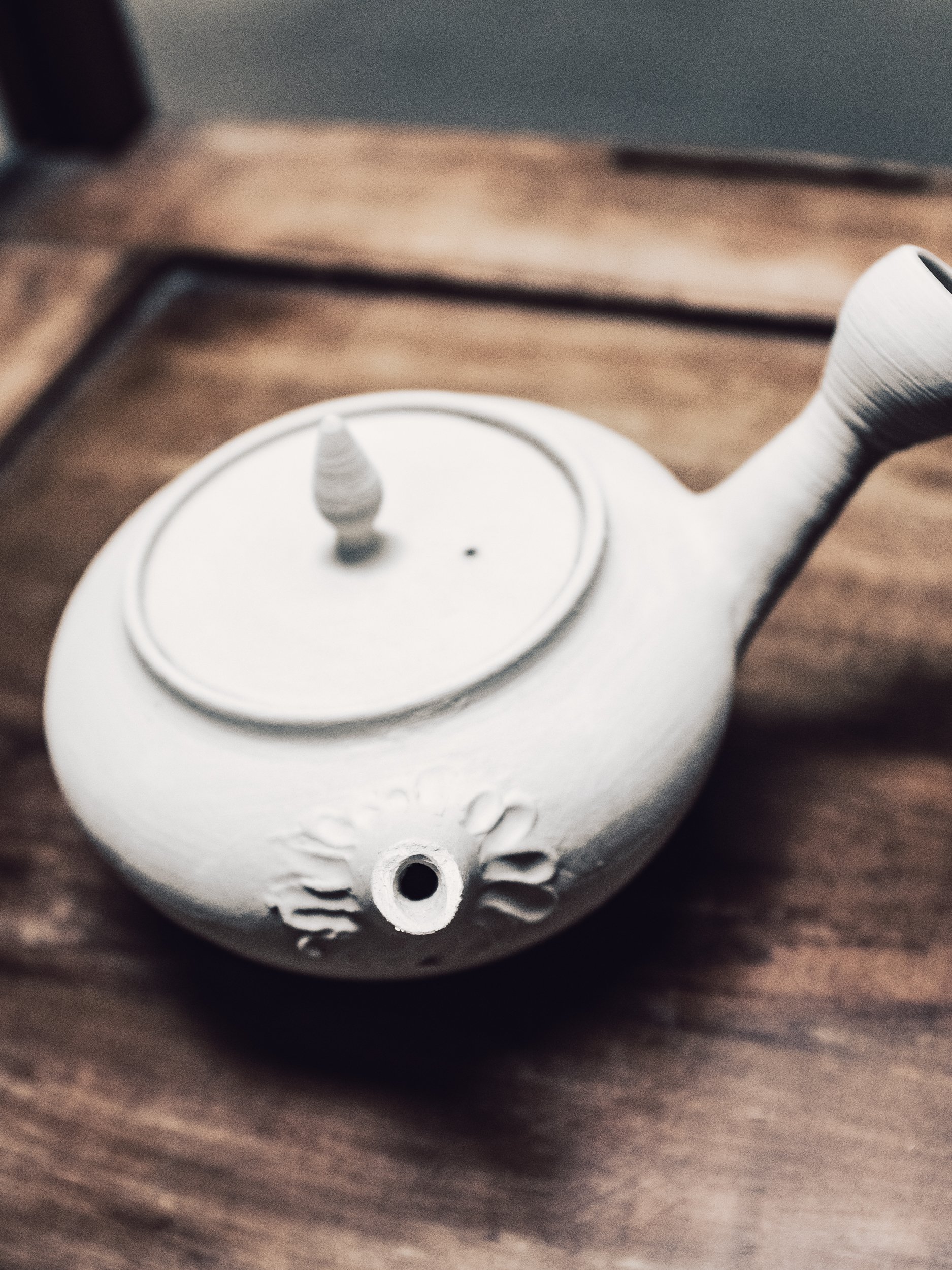 White ceramic teapot with intricate design on wooden surface