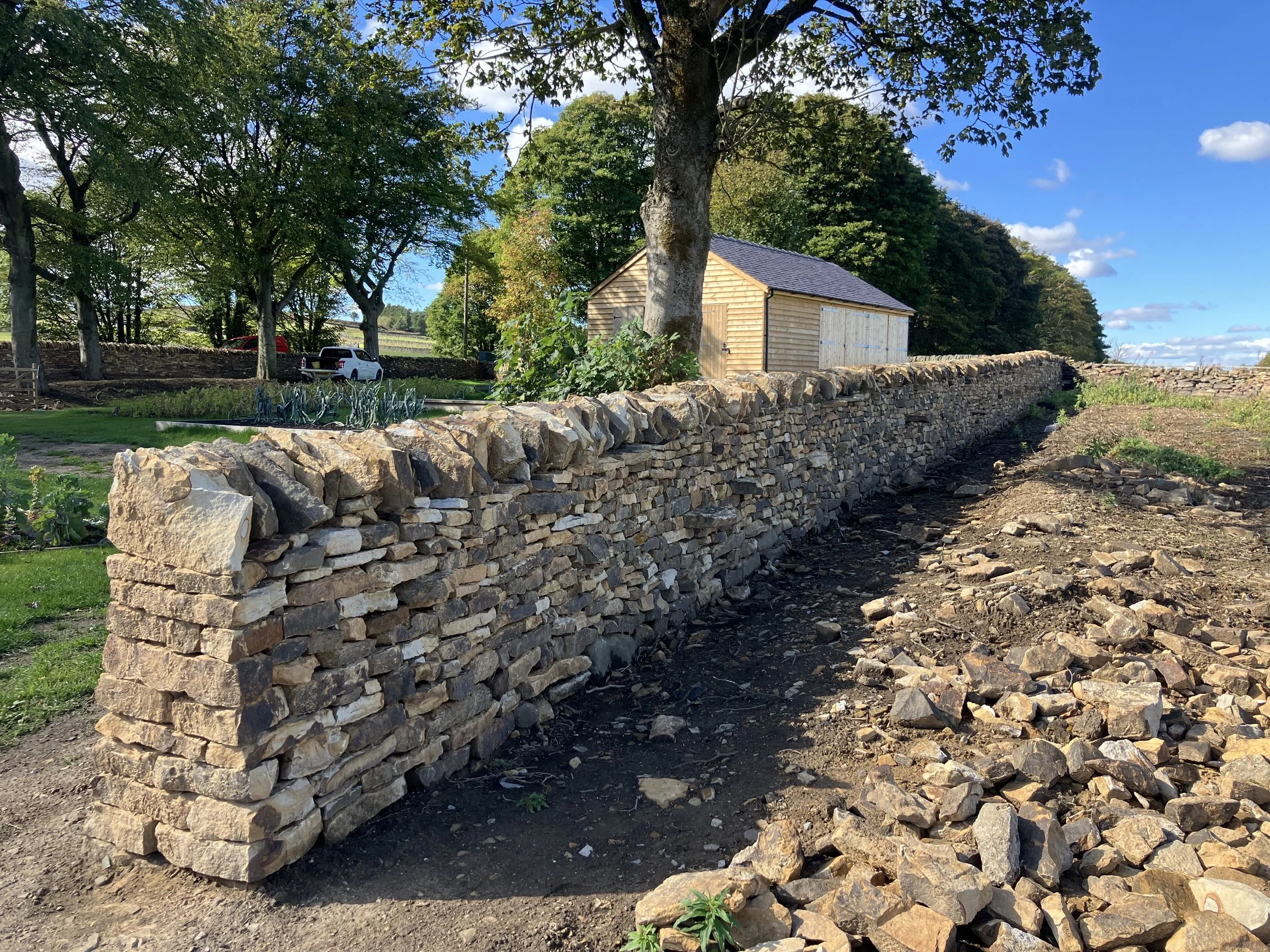 Drystone wall under construction in a rural peak district garden.