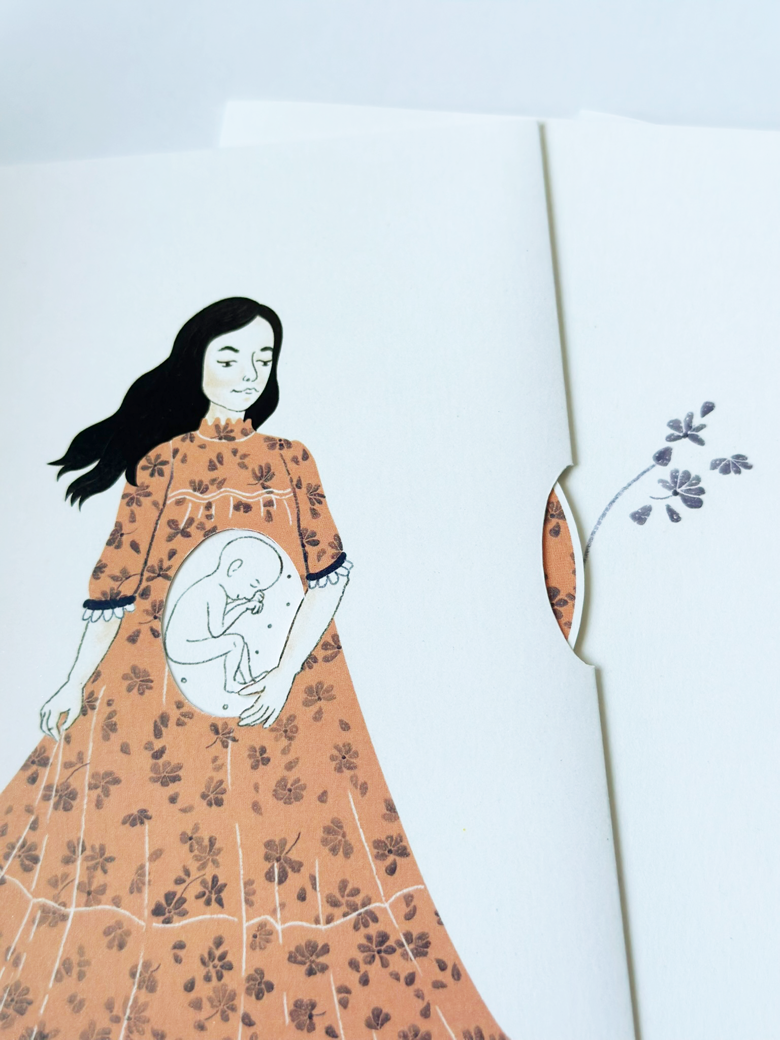 Ilustrace ženy s dlouhými tmavými vlasy v oranžových květinových šatech, s náčrtem těhotenského břicha ukazujícího miminko uvnitř, na bílém pozadí s malou květinou napravo.