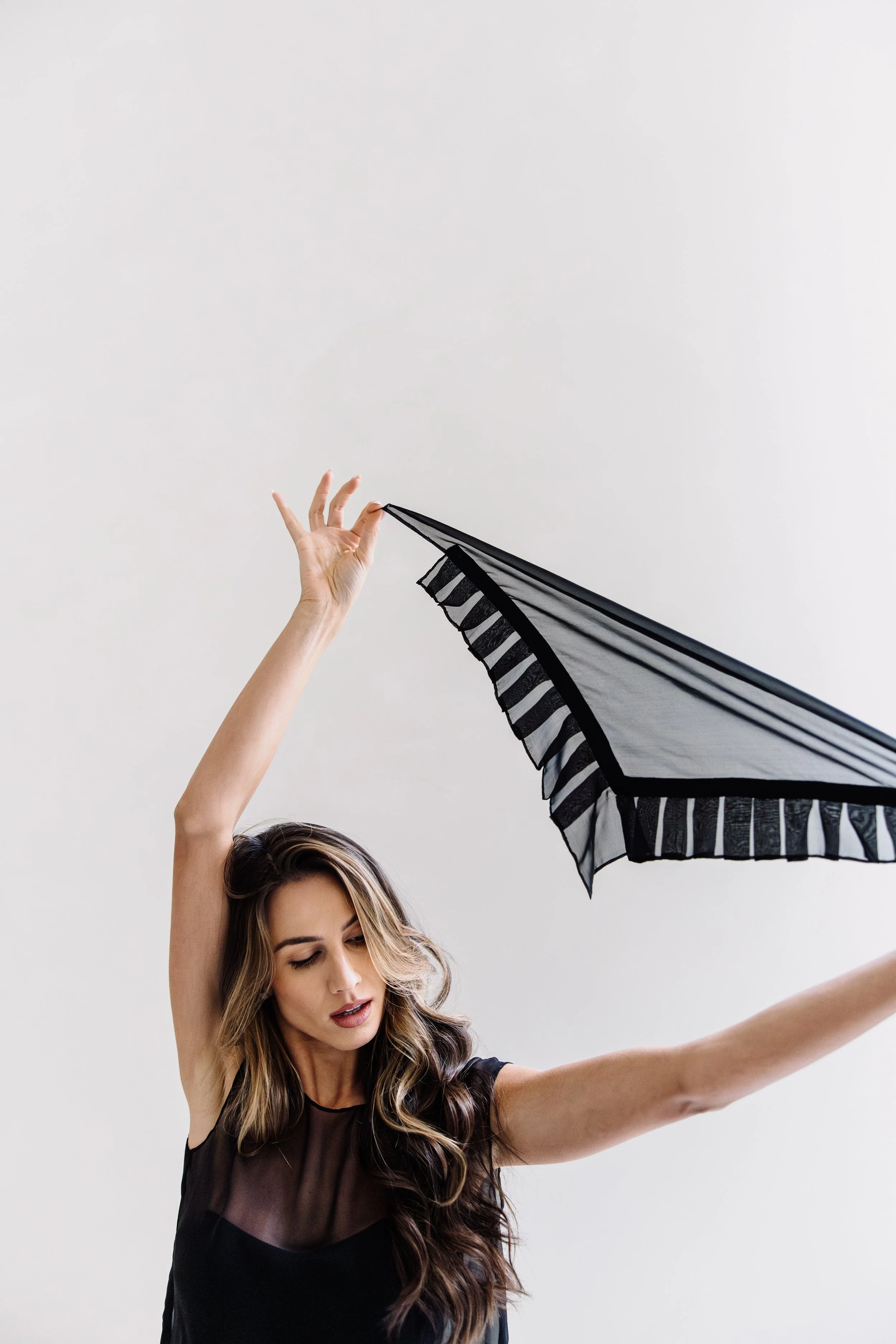 A woman holding a black and white striped umbrella with a plain white background.