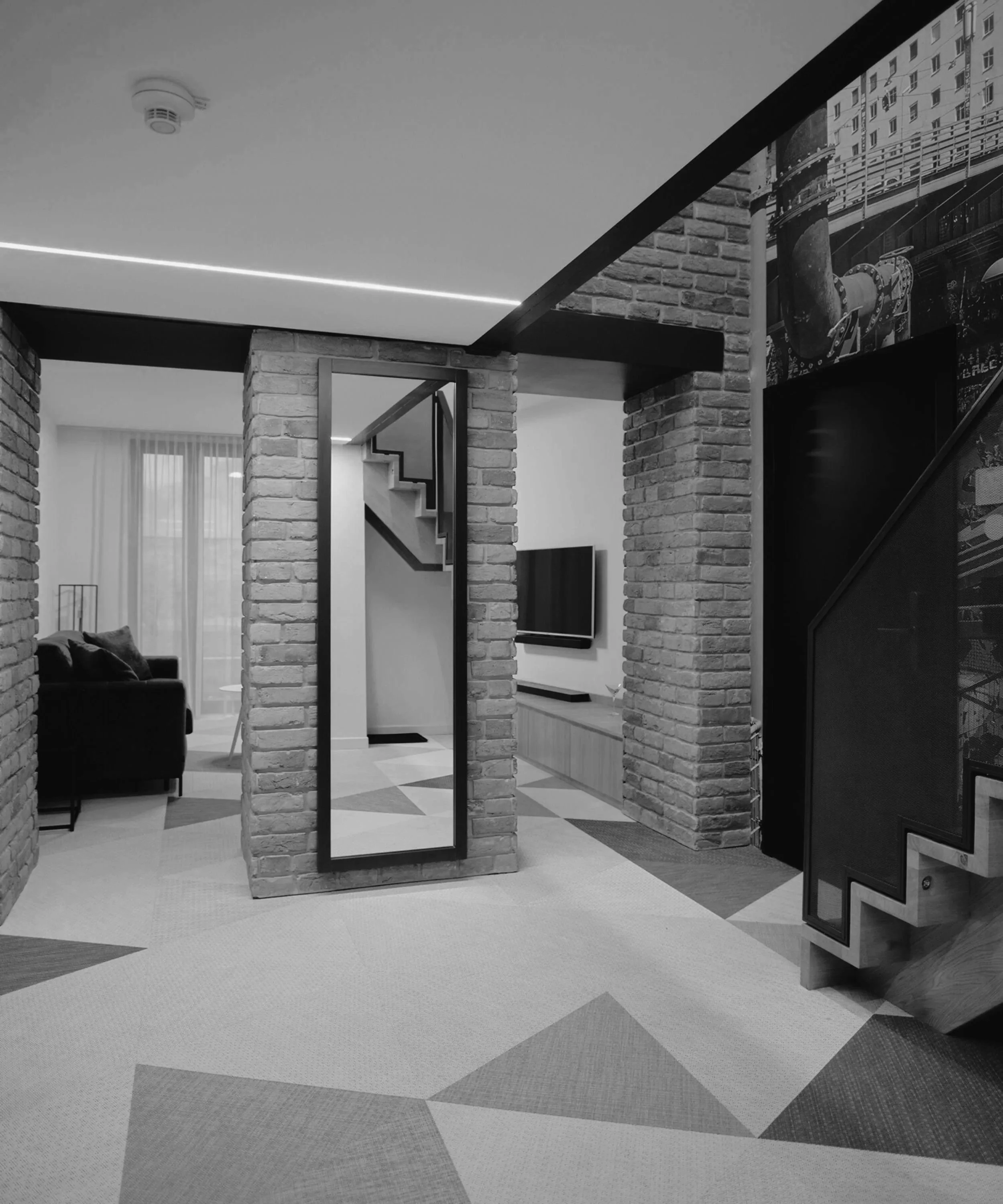 Modern living room with exposed brick walls, a staircase, and a flat-screen TV