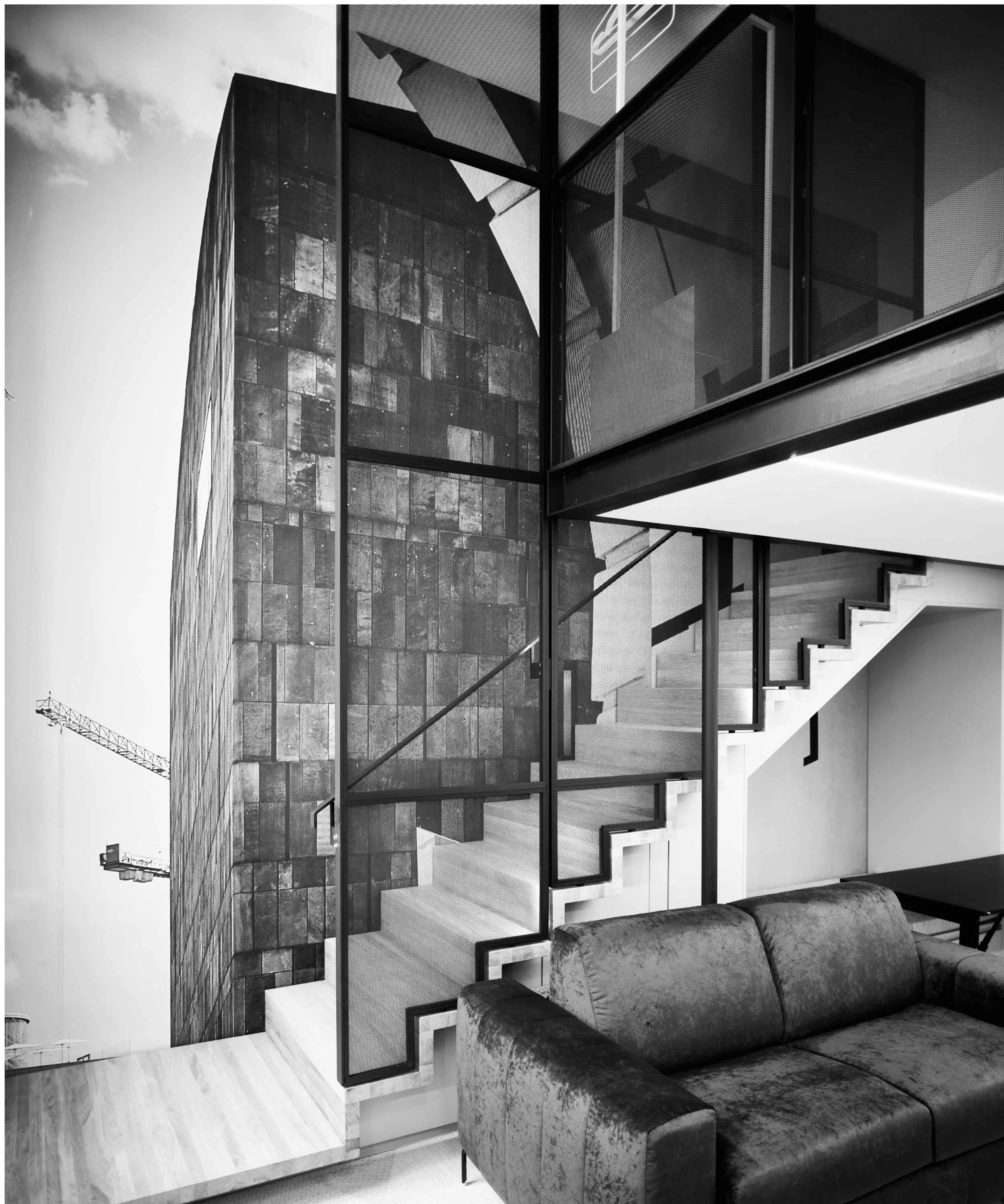 Interior view of a modern, minimalist living space with a staircase, glass walls, and a velvet sofa, featuring contemporary architectural design.