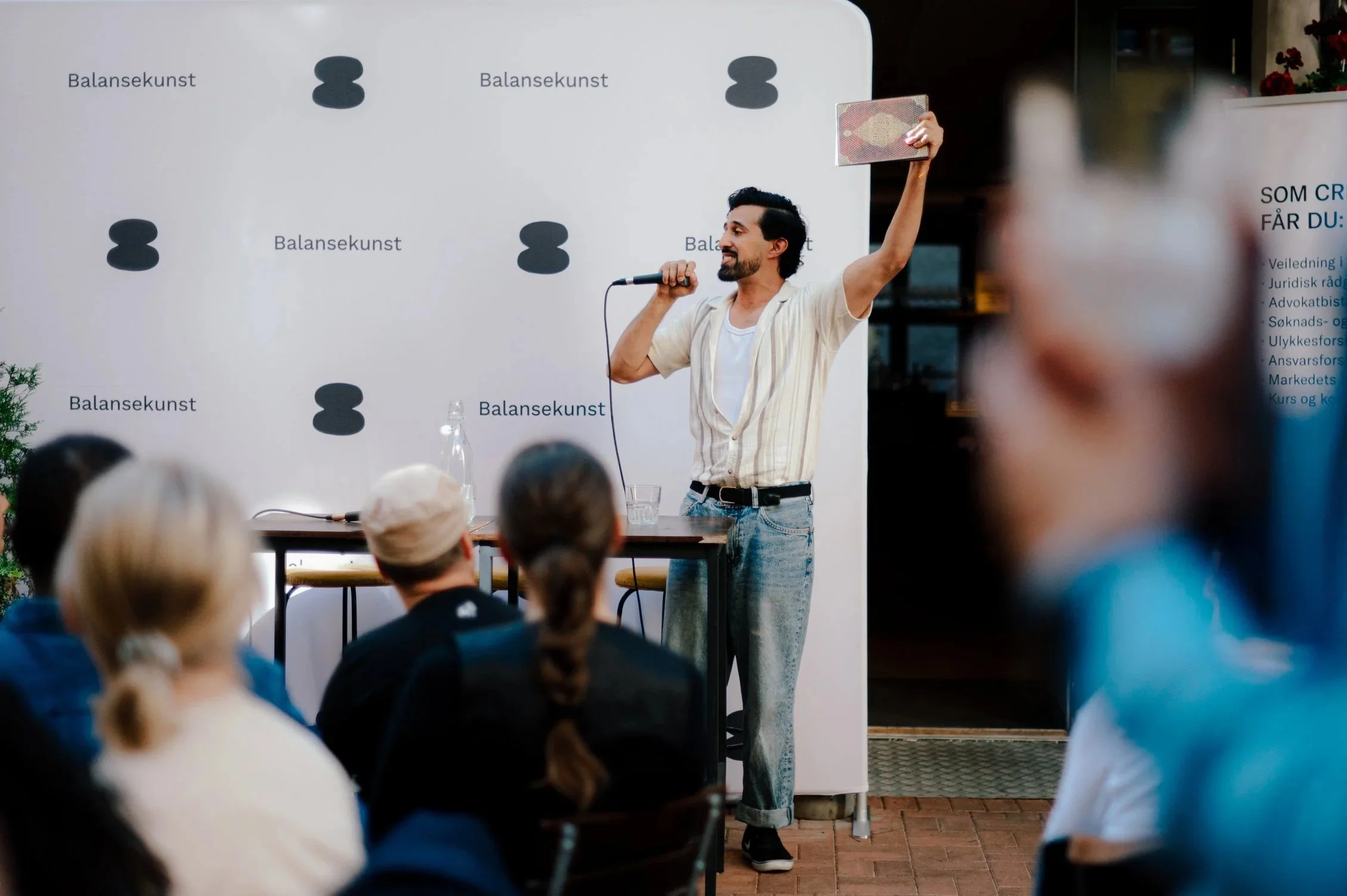 Slampoet Jawad Aziz på scene foran et publikum utendørs.